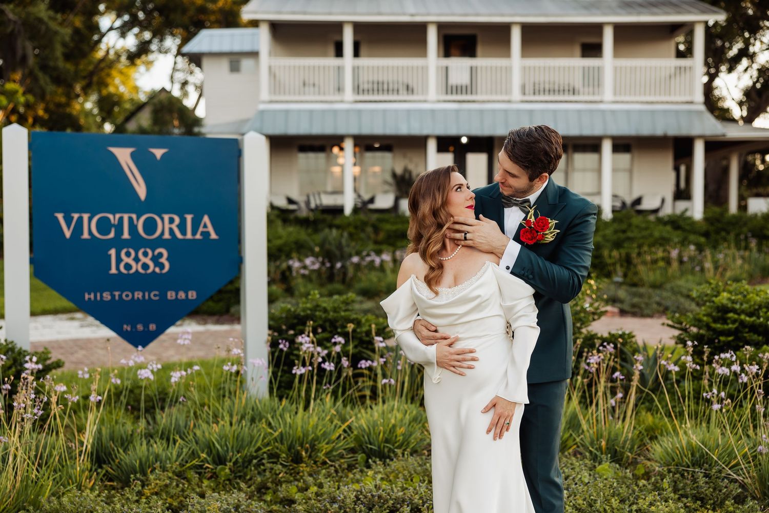 Newlyweds embrace in front of historic Victoria 1863 building sign.
