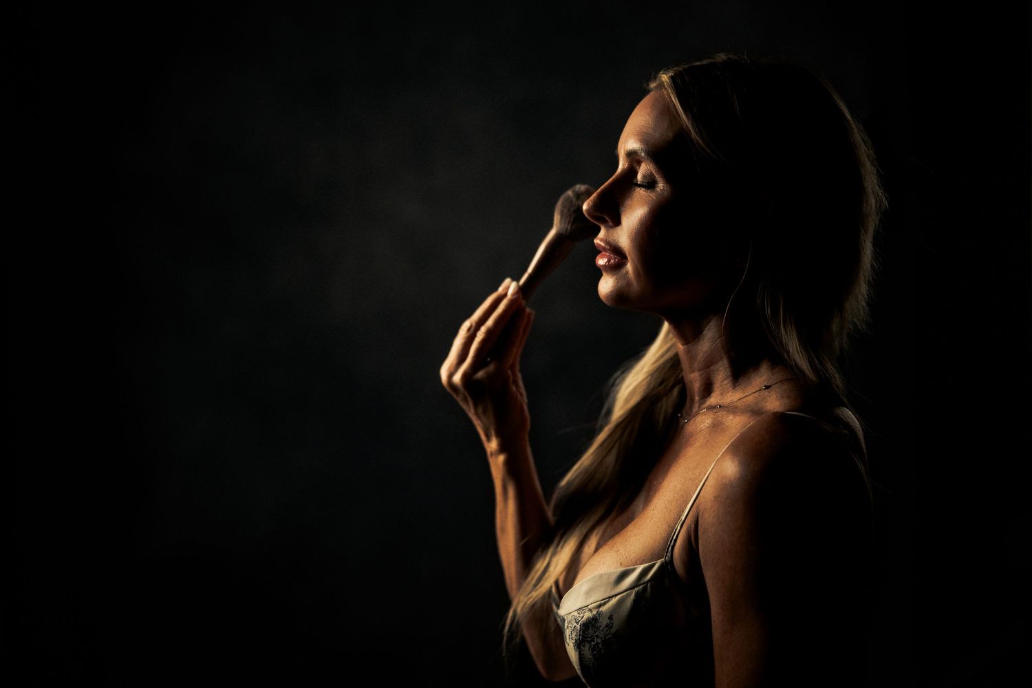Artistic silhouette portrait with dramatic side lighting against dark background.