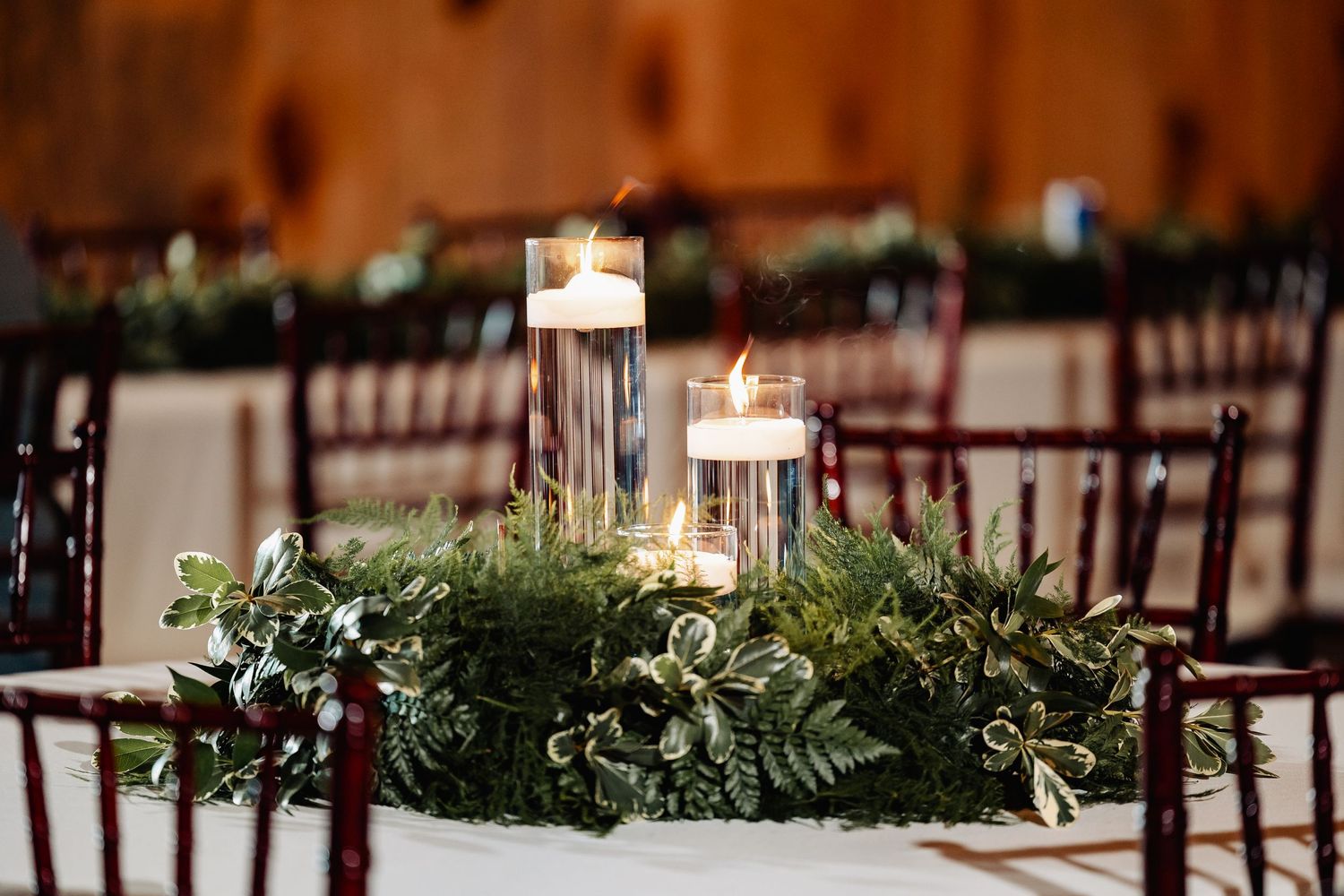 Wedding reception table centerpiece with floating candles and fresh greenery.
