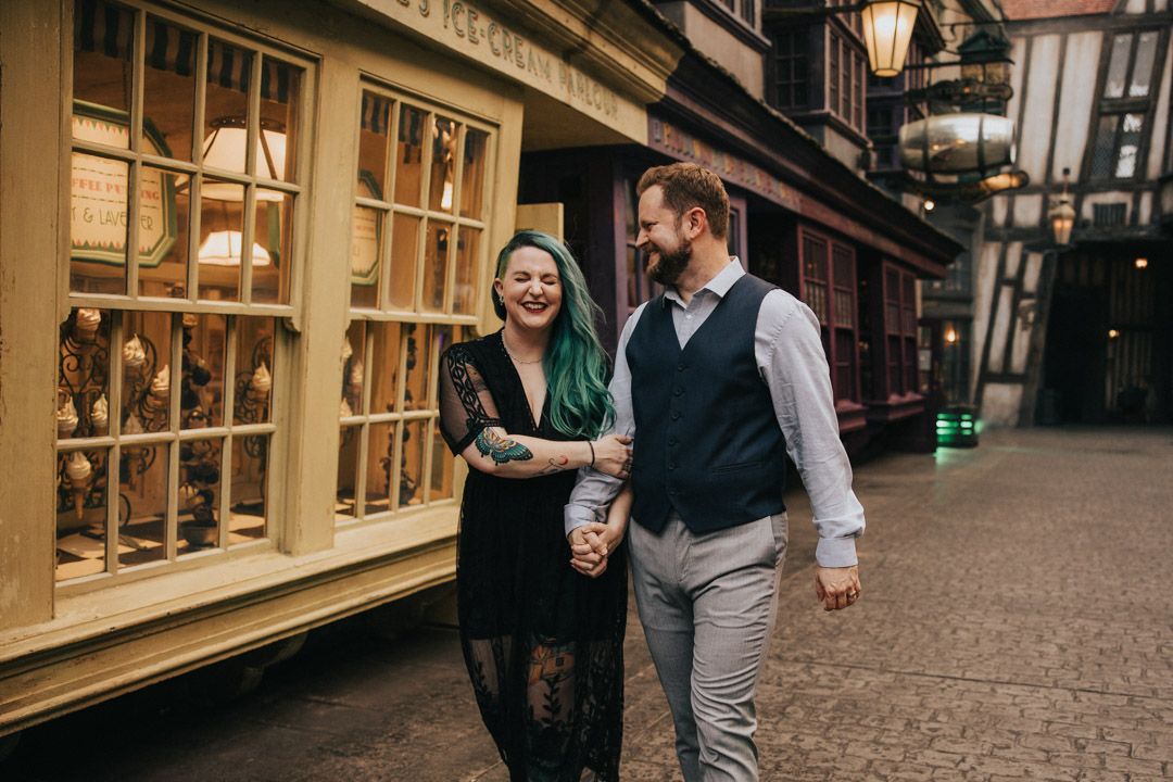 Couple walking hand in hand past a shop window in the Wizarding World of Harry Potter.