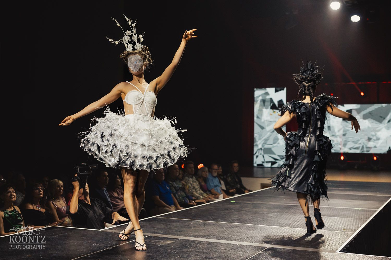 Contemporary dancers performing in black costumes on illuminated stage.