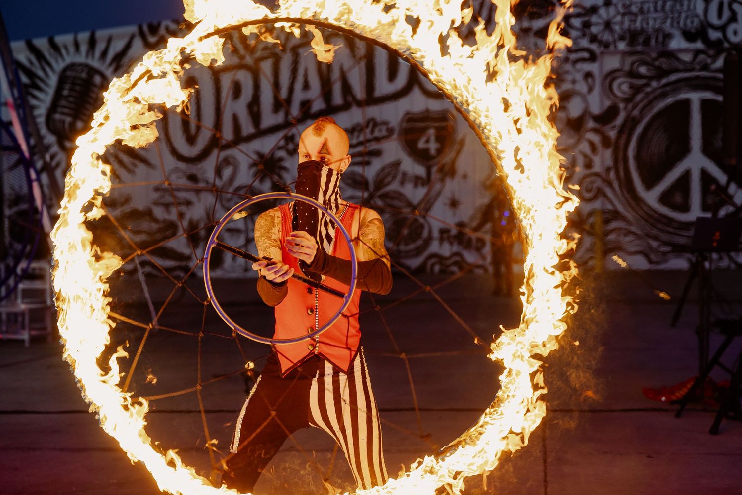 Circus performer standing inside a flaming fire ring at Orlando circus show at night.