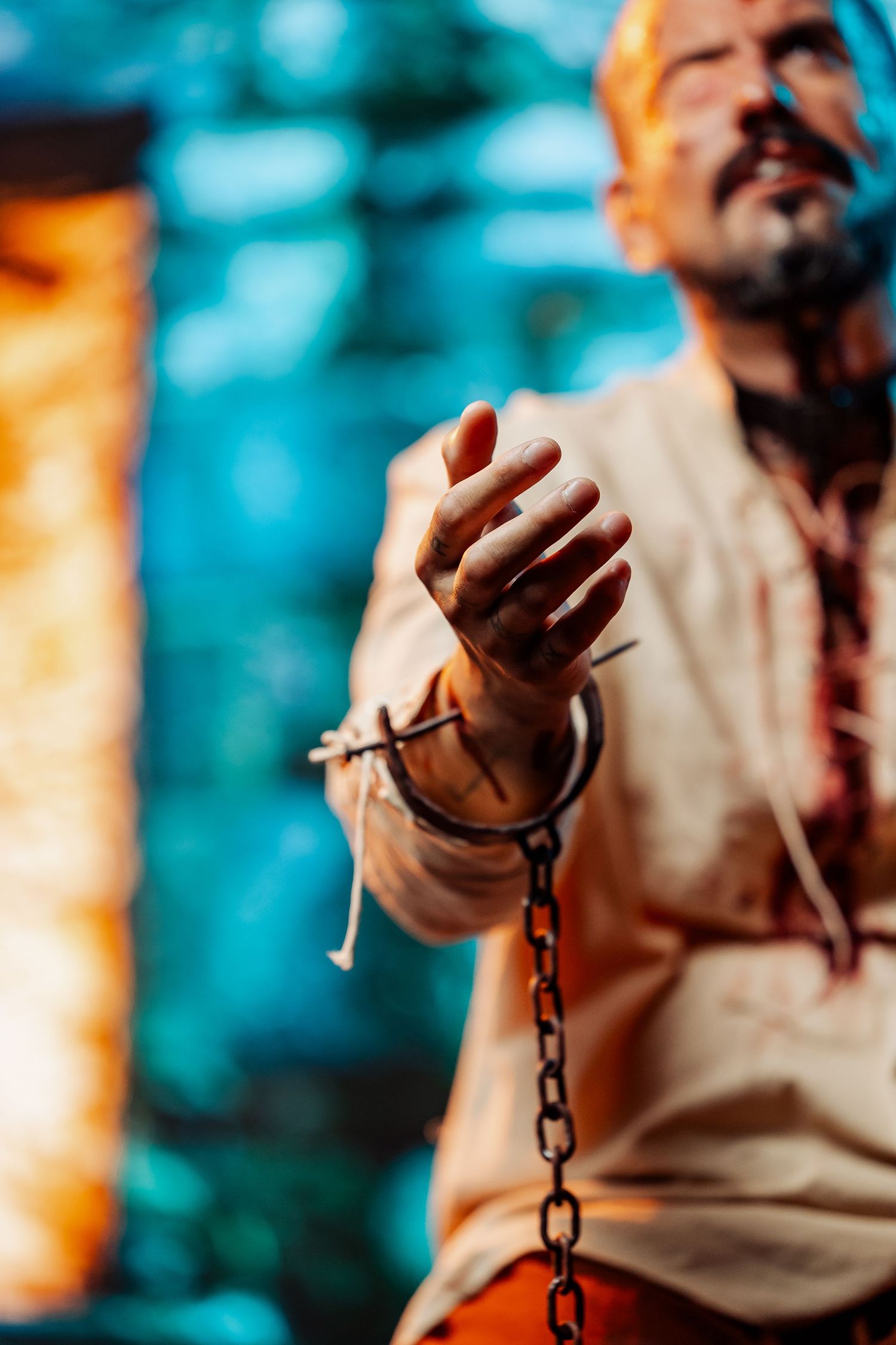 Close-up of chained hands with barbed wire in a dramatic Halloween or theatrical costume performance.
