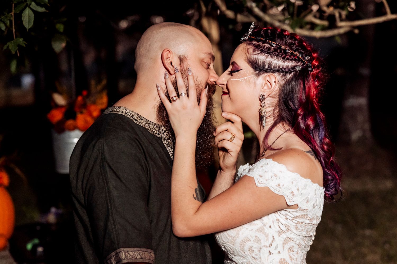 Intimate wedding moment captured under trees with autumn décor and ambient lighting.