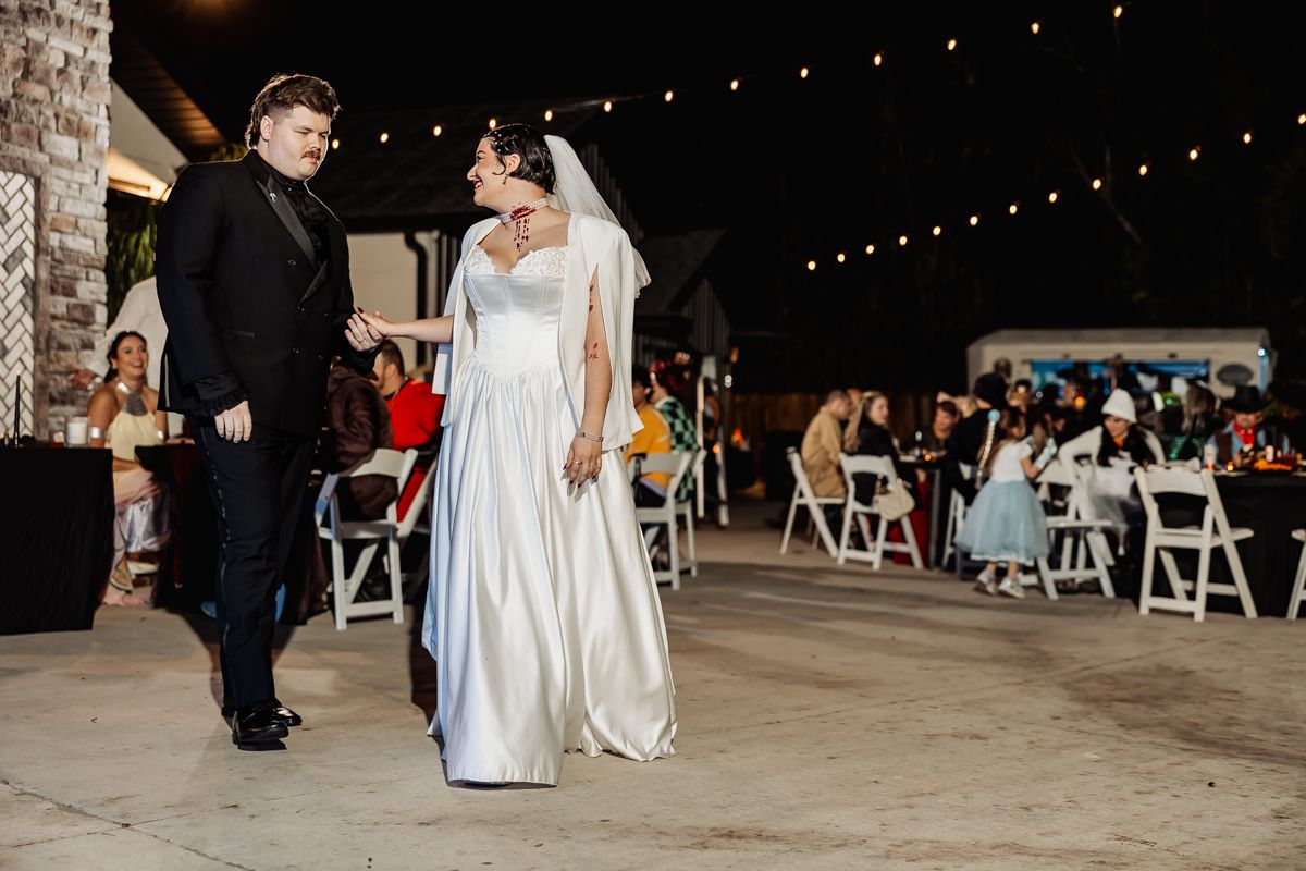 A wedding reception celebration in a rustic barn venue with string lights and white chairs creating a romantic atmosphere.