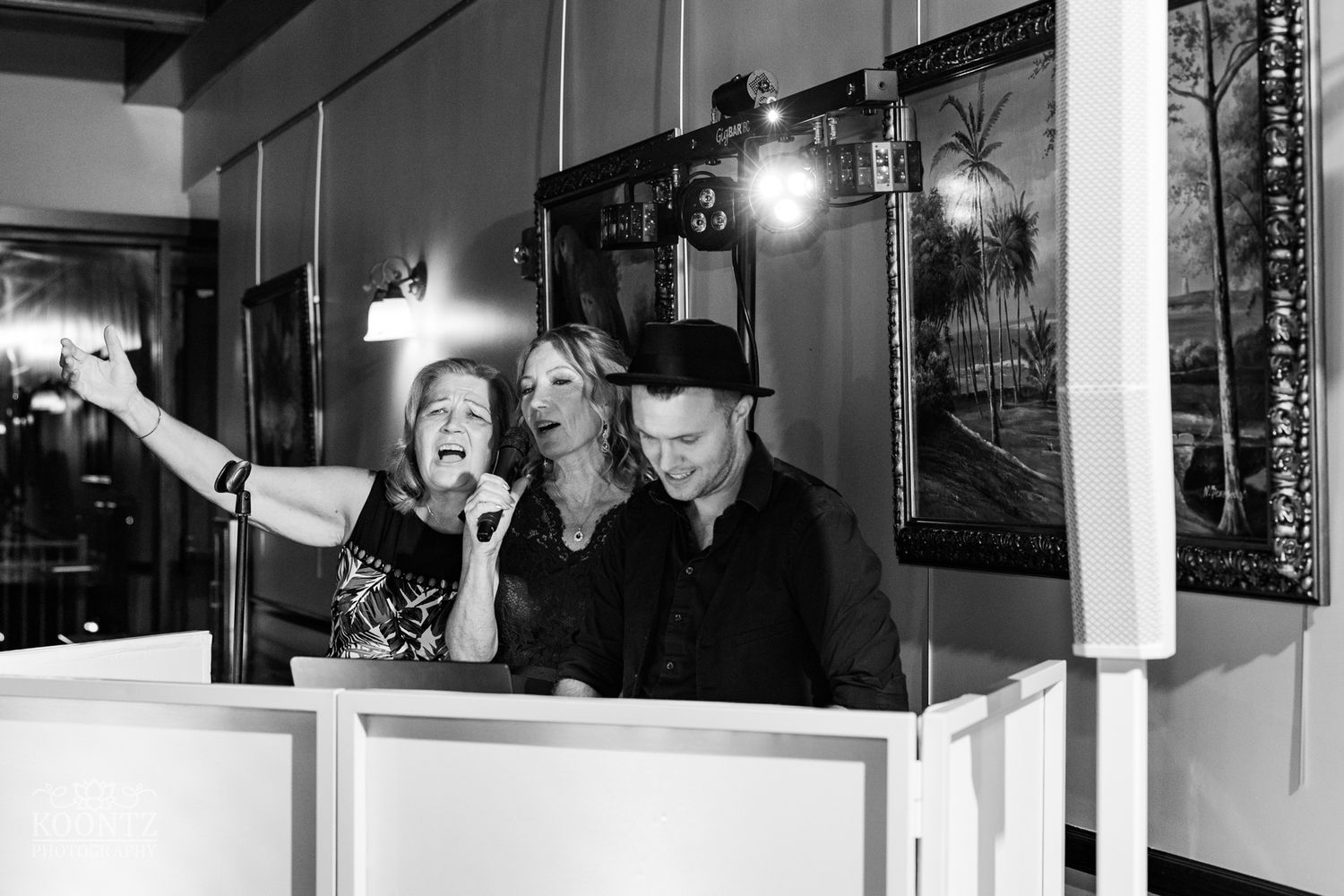 DJ booth at wedding reception with energetic performers entertaining the crowd in black and white.