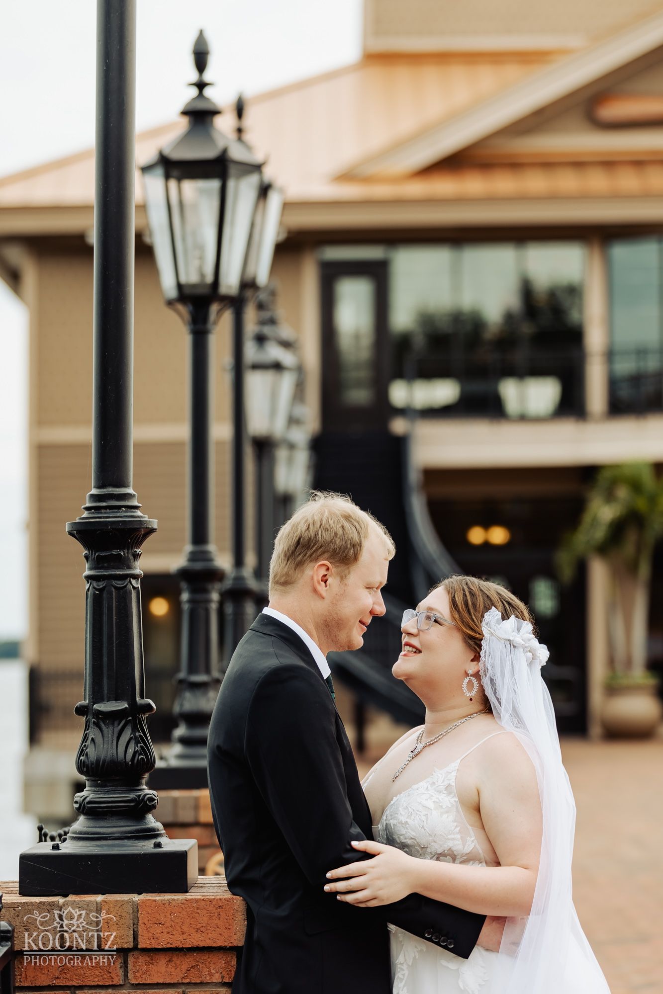 A tender moment between newlyweds near a vintage street lamp outside an elegant venue.