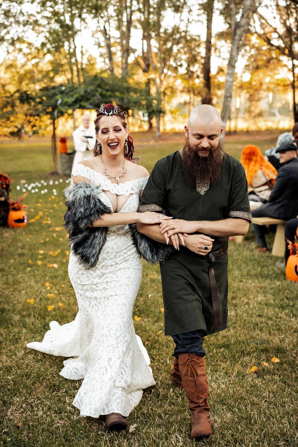 A joyful wedding moment captured outdoors with autumn decor and pumpkins in the background.