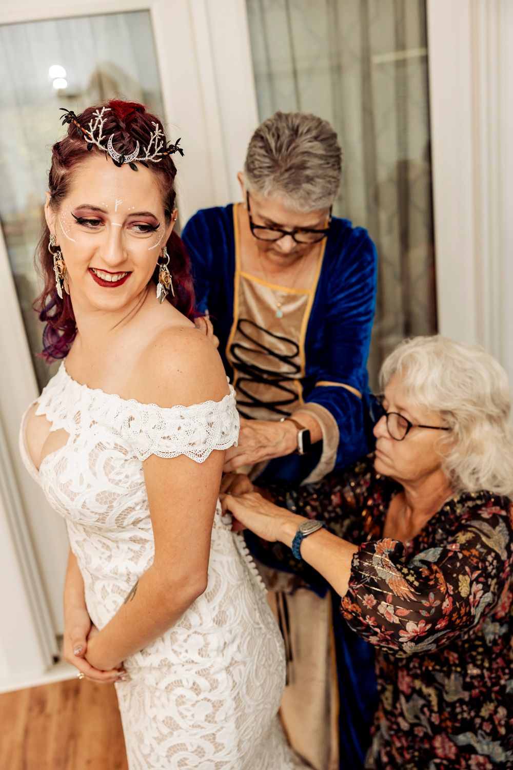 A tender moment during wedding preparations featuring an elegant lace wedding dress and silver crown.