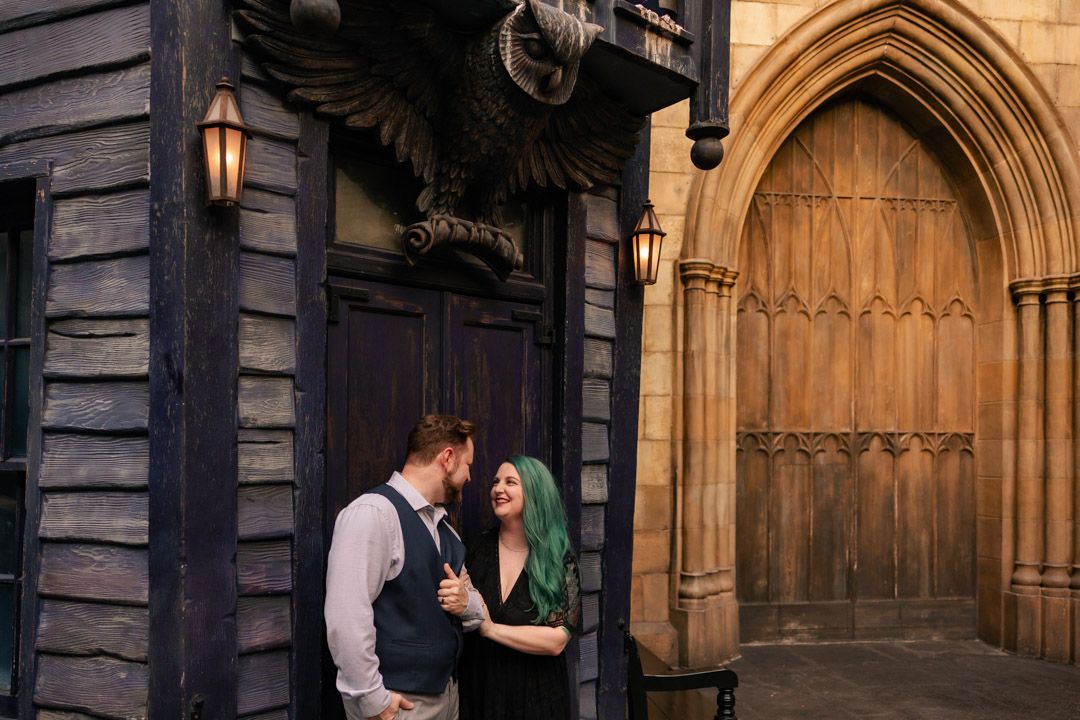 Couple sharing a romantic moment near a Gothic wooden door at Wizarding World of Harry Potter.