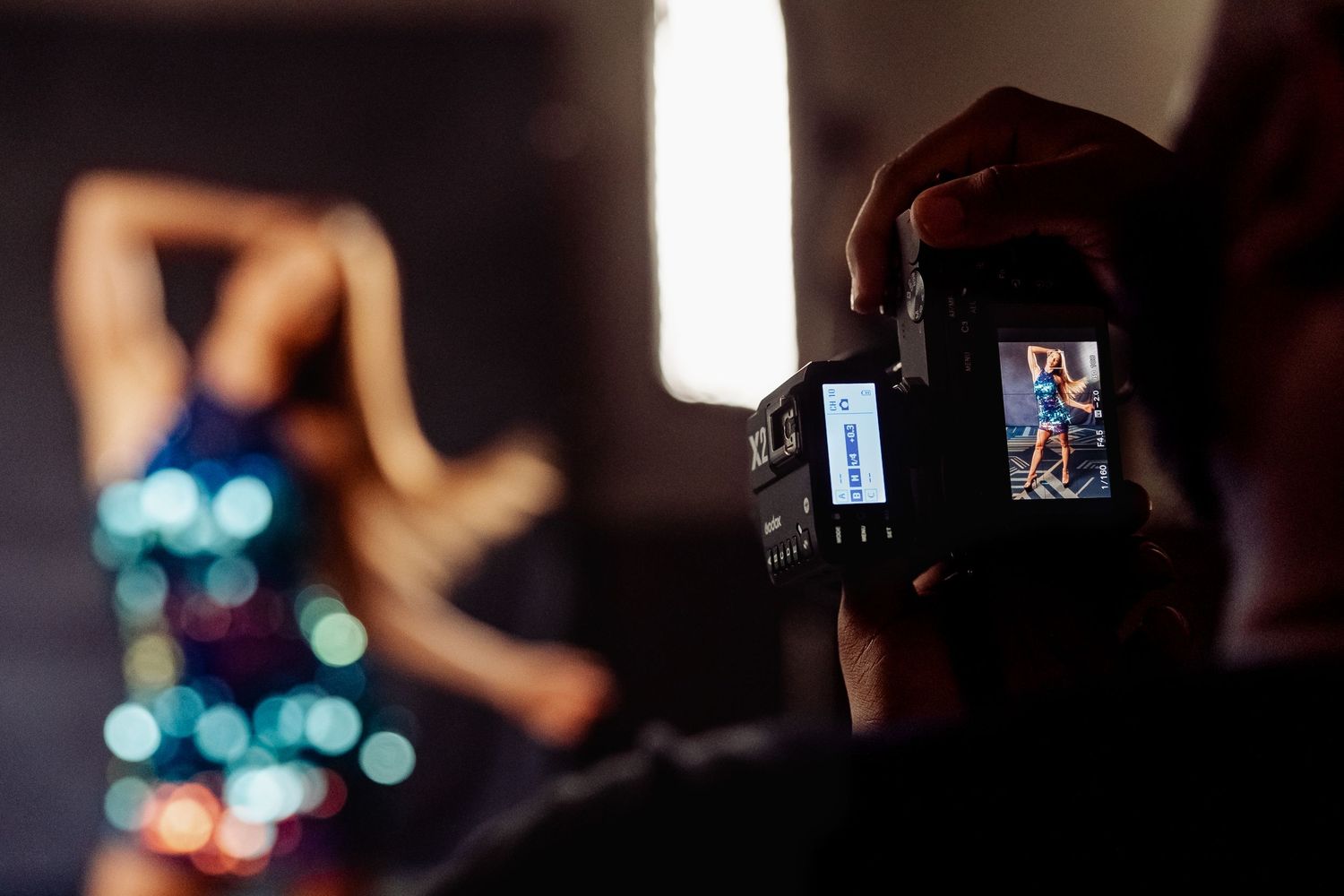 Camera display showing model shoot with bokeh lights in background.