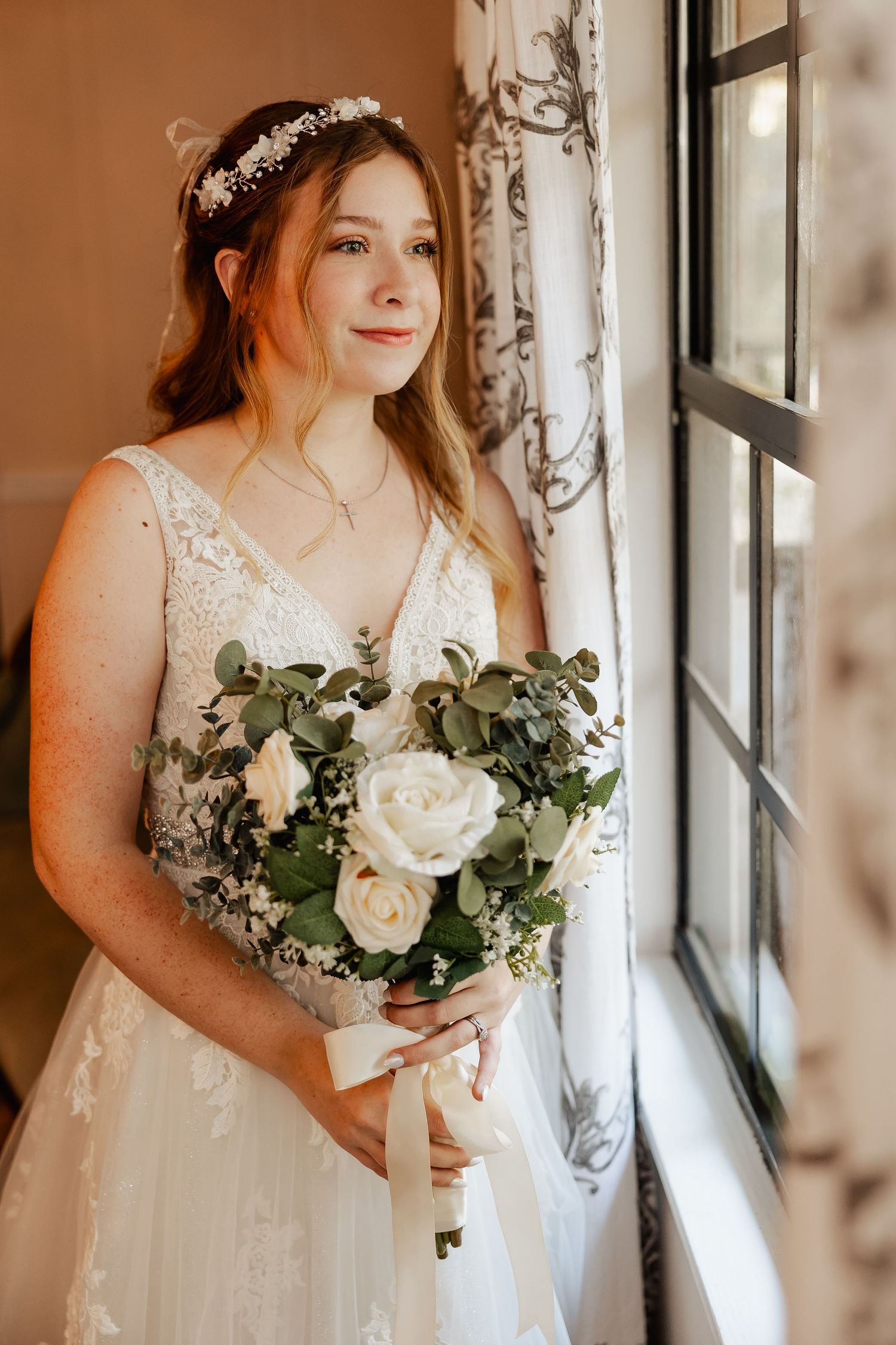 Elegant bridal portrait with white rose bouquet by window with natural light.