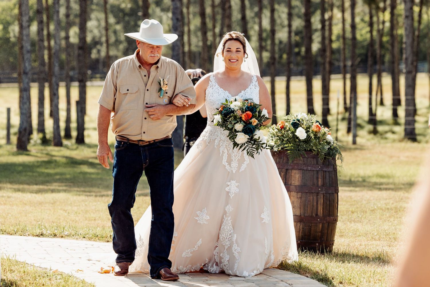 Couple walking down stone path at outdoor country wedding ceremony.