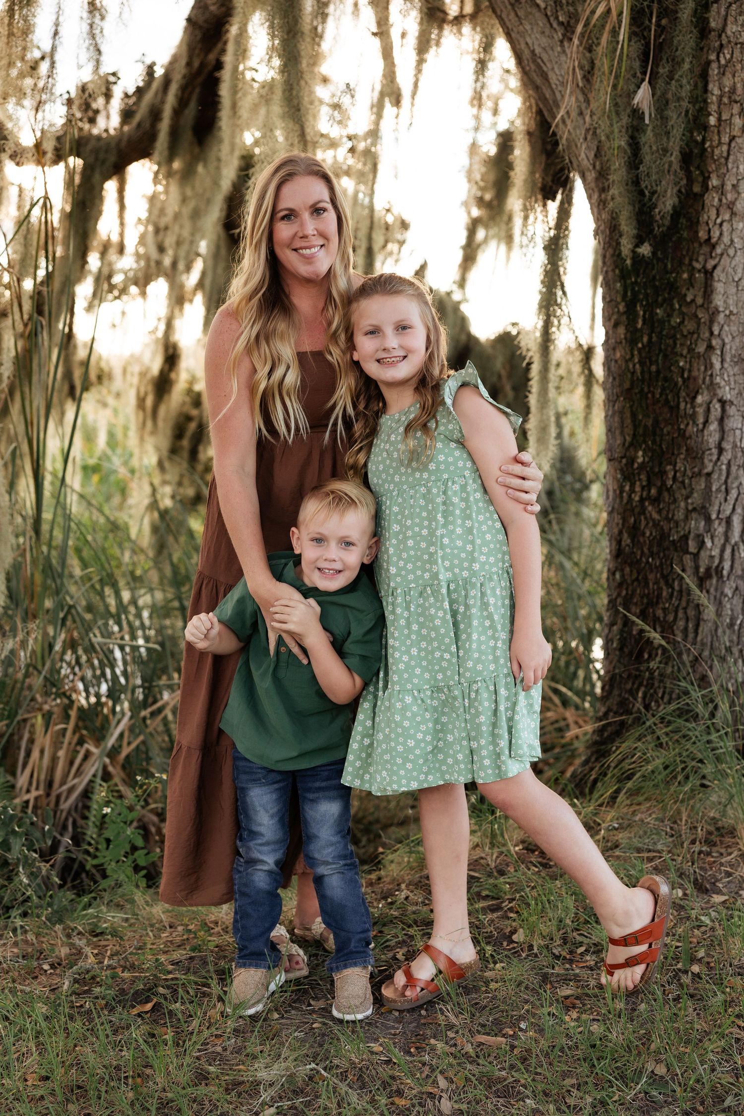 Family portrait under Spanish moss with coordinating brown and green outfits.