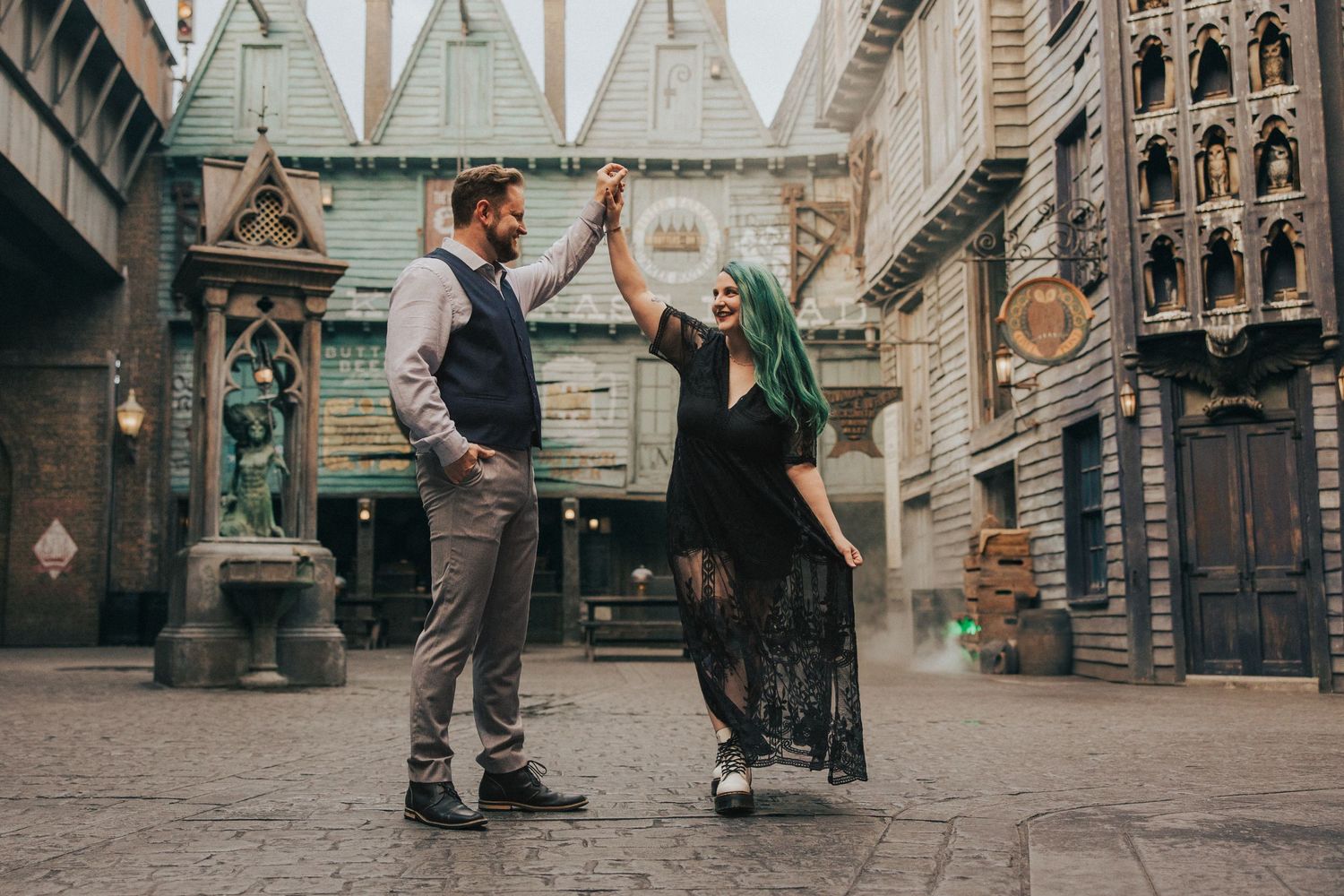 Couple dancing joyfully in fantasy-themed street with gothic architecture background.