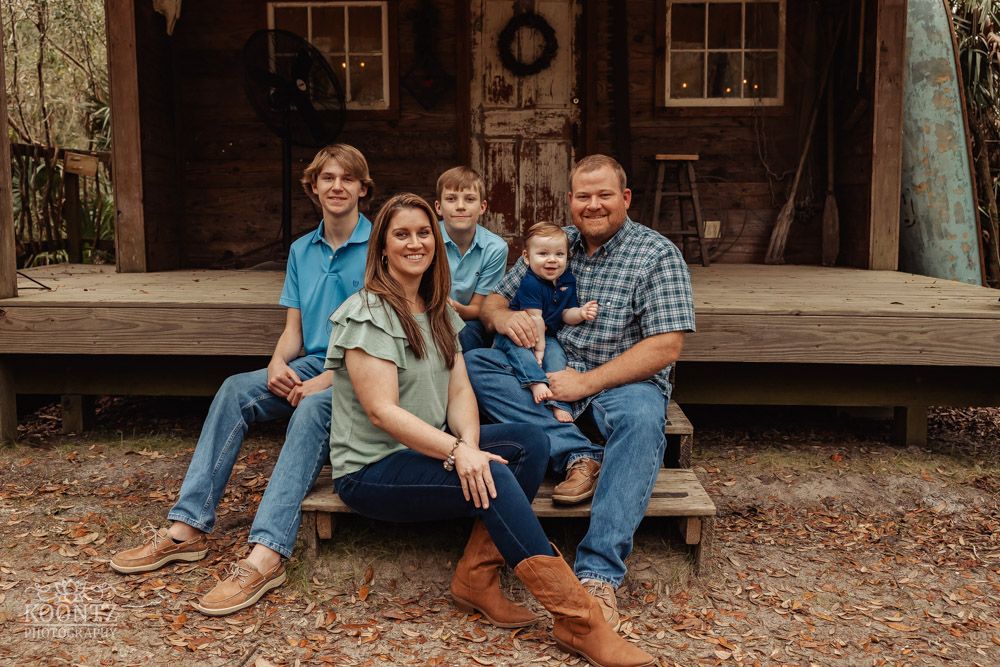 A family portrait on a rustic wooden porch with casual attire.