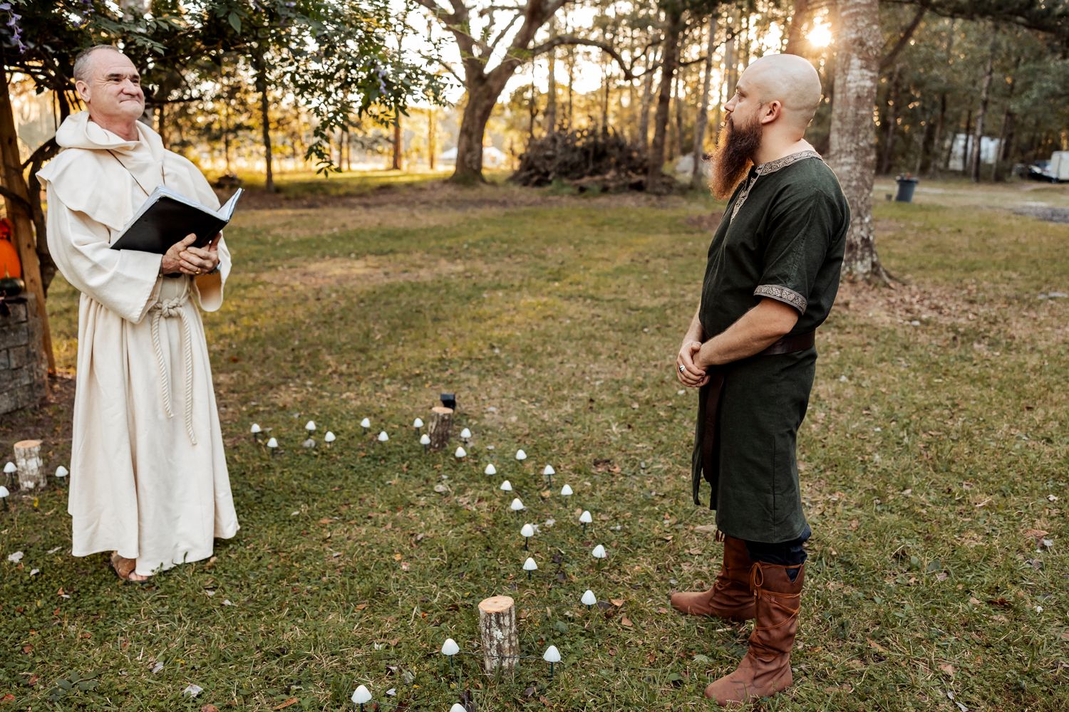 An outdoor ceremony setup at sunset with candles lining the aisle and trees in the background.