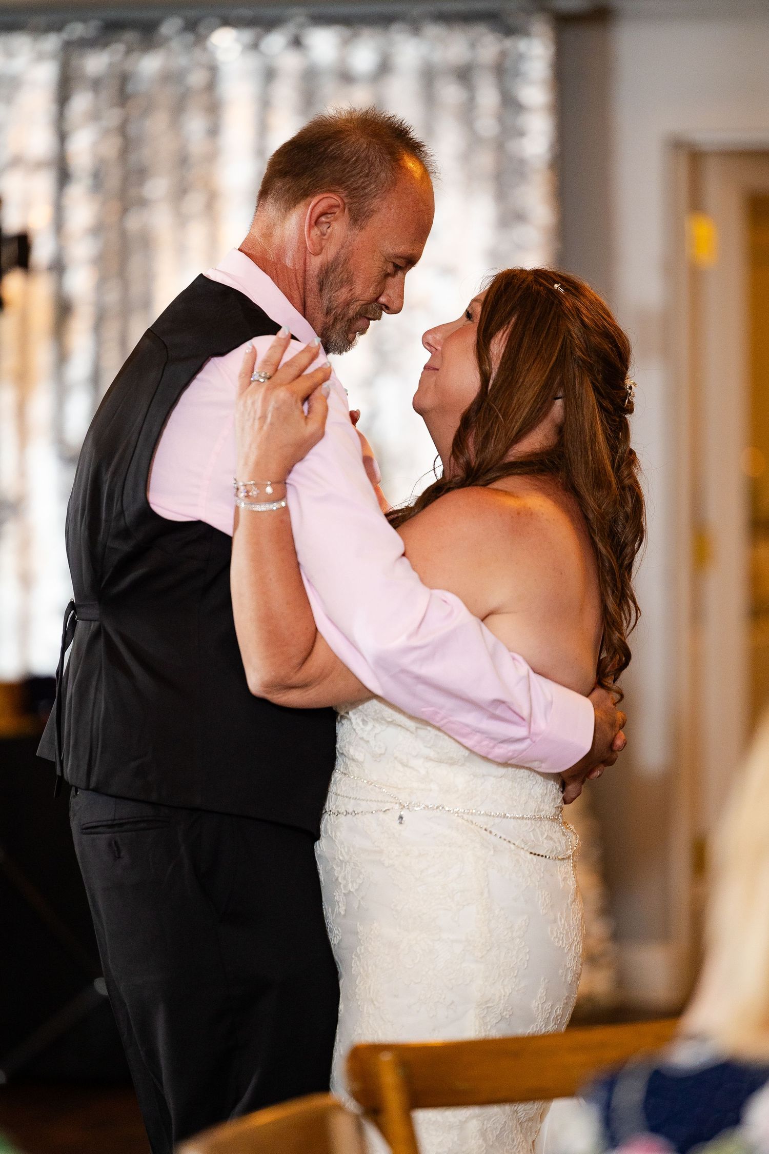 Bride and groom share an intimate first dance embrace, gazing lovingly at each other at wedding reception.