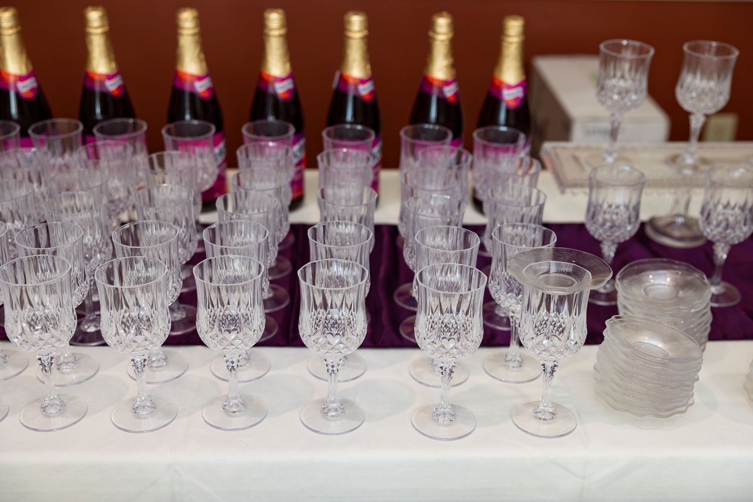 Elegant crystal glassware and champagne bottles arranged on a white tablecloth for a formal event.