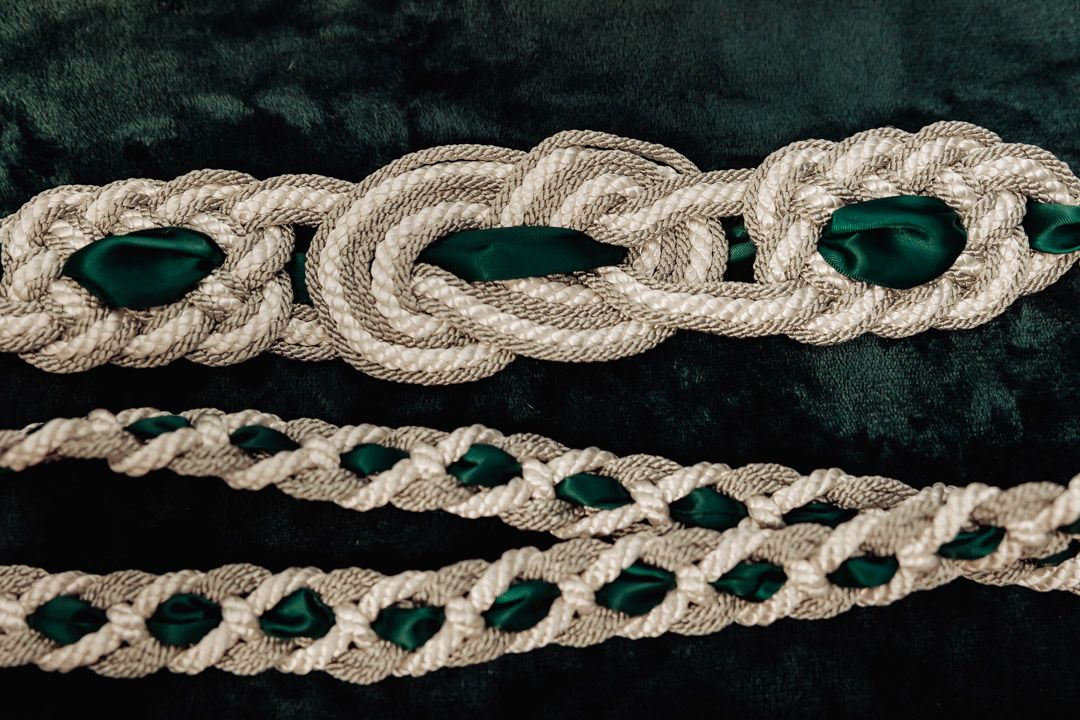 Decorative silver braided rope trim against dark green velvet background.