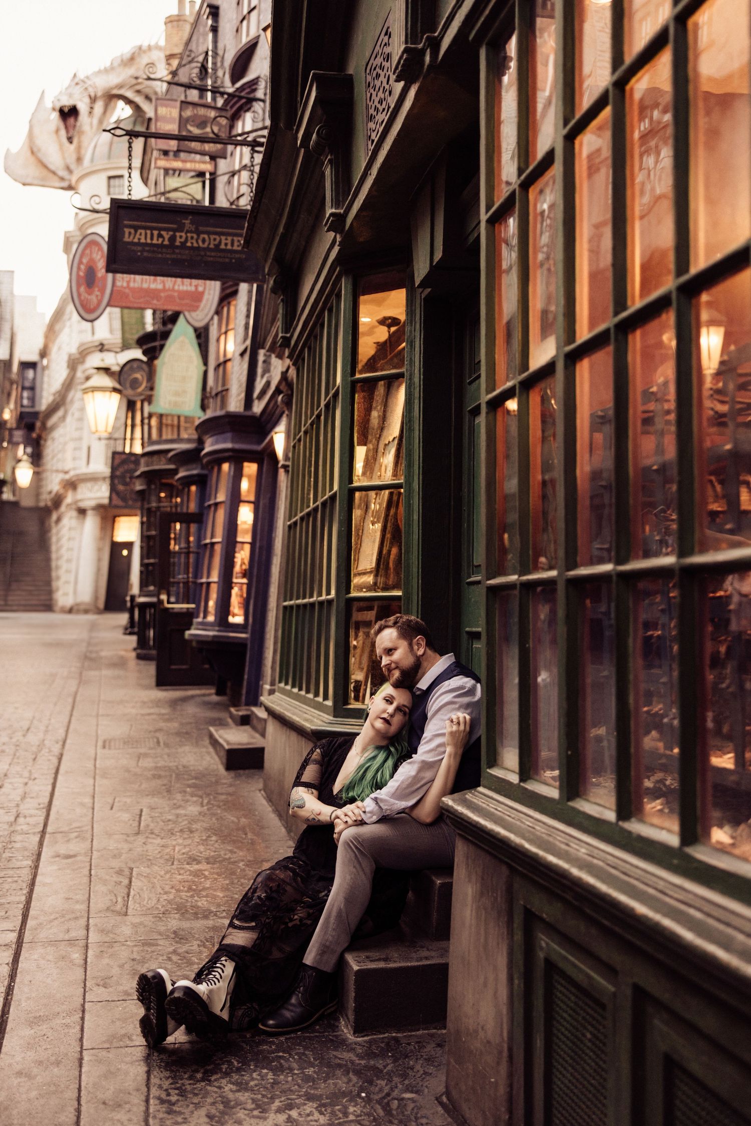 A couple rests intimately on stone steps along a historic shopping street.