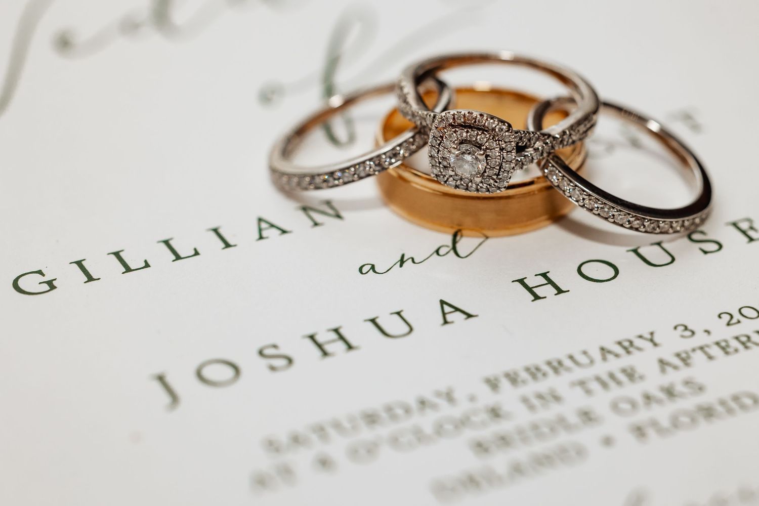 Wedding rings and invitation card with names displayed in elegant typography.