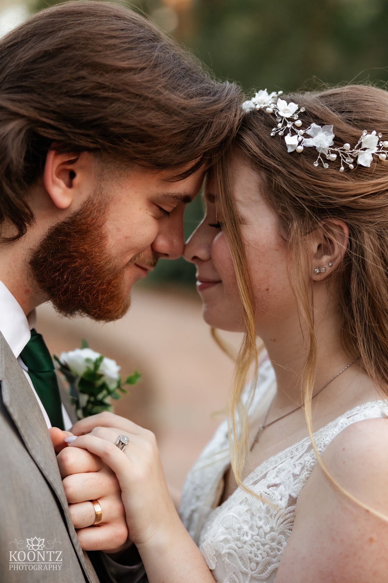 Bride and groom share an intimate forehead touch moment, bride wearing floral hair vine on wedding day.