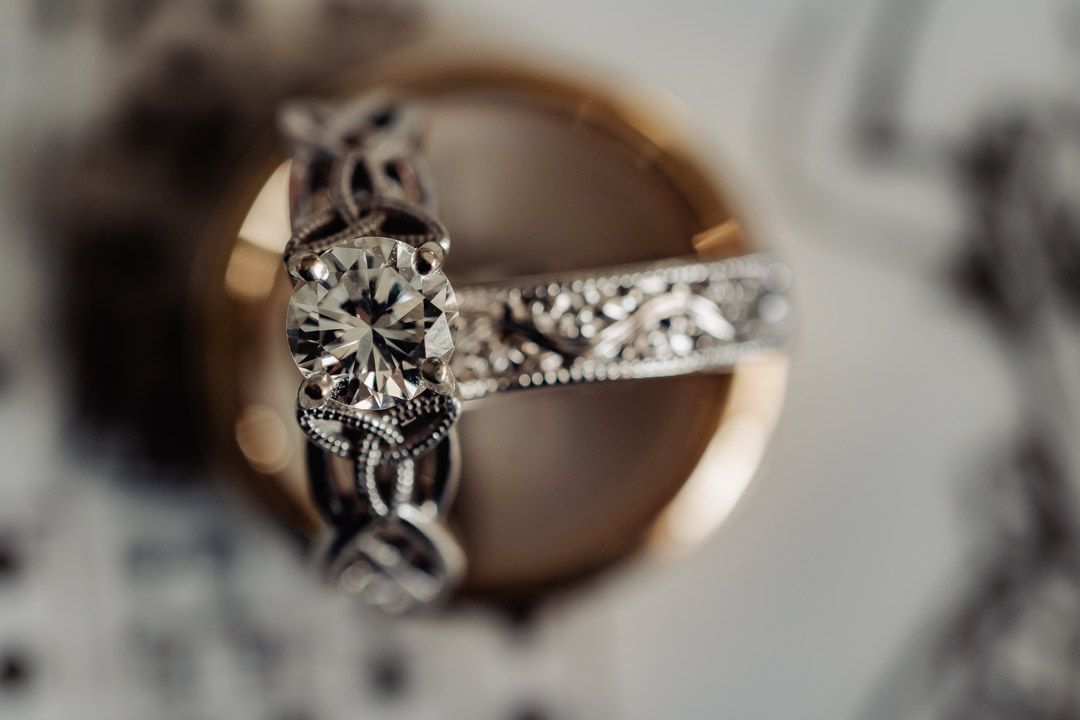 Close-up macro shot of a vintage-style diamond engagement ring with intricate filigree band detailing.