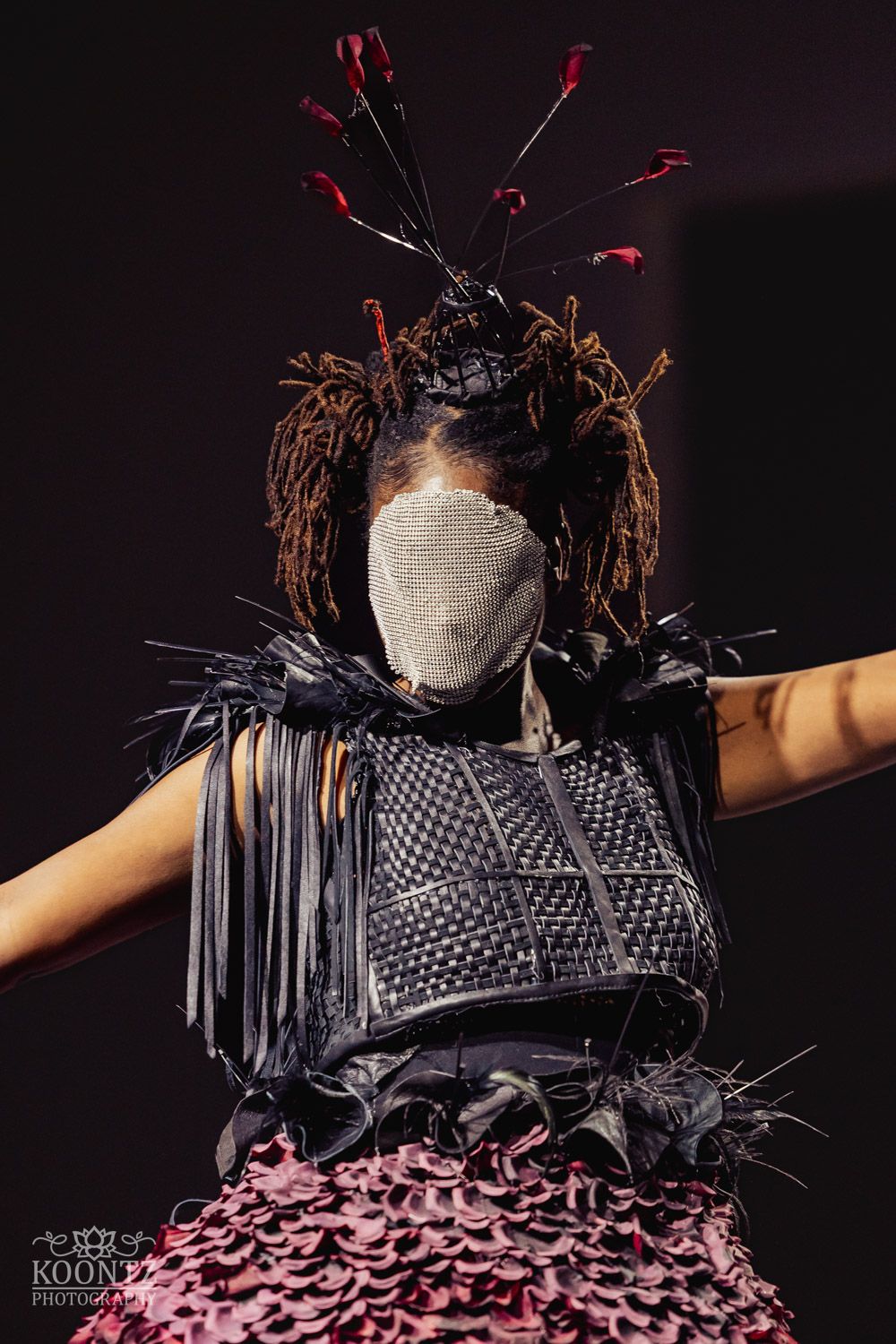 Artistic fashion piece featuring metallic details and pink ruffled skirt on dark background.