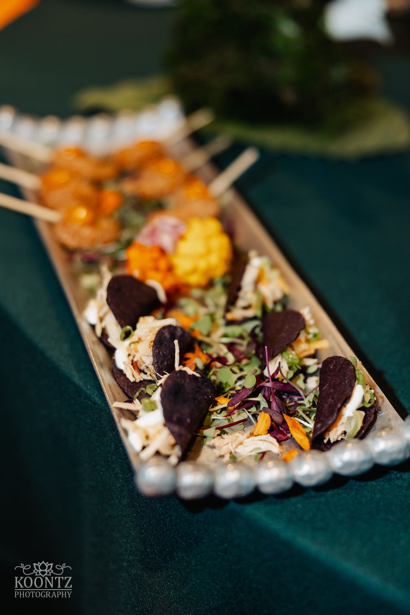 Elegant appetizer platter with dark garnishes served on an elongated wooden board.