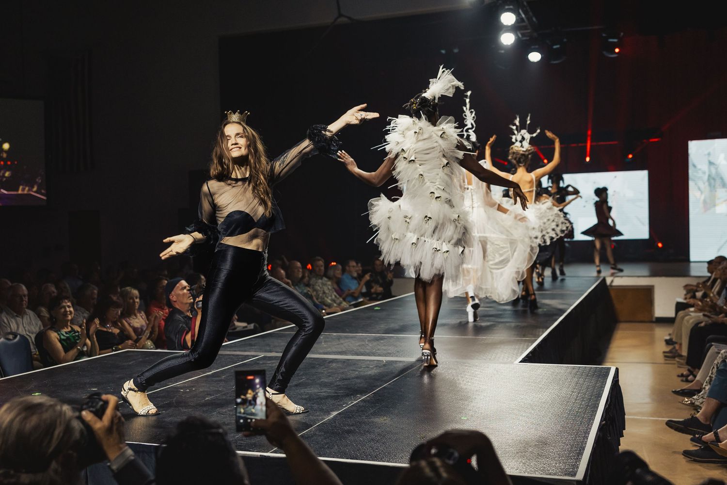 Models in contrasting black and white avant-garde costumes perform on fashion show runway.