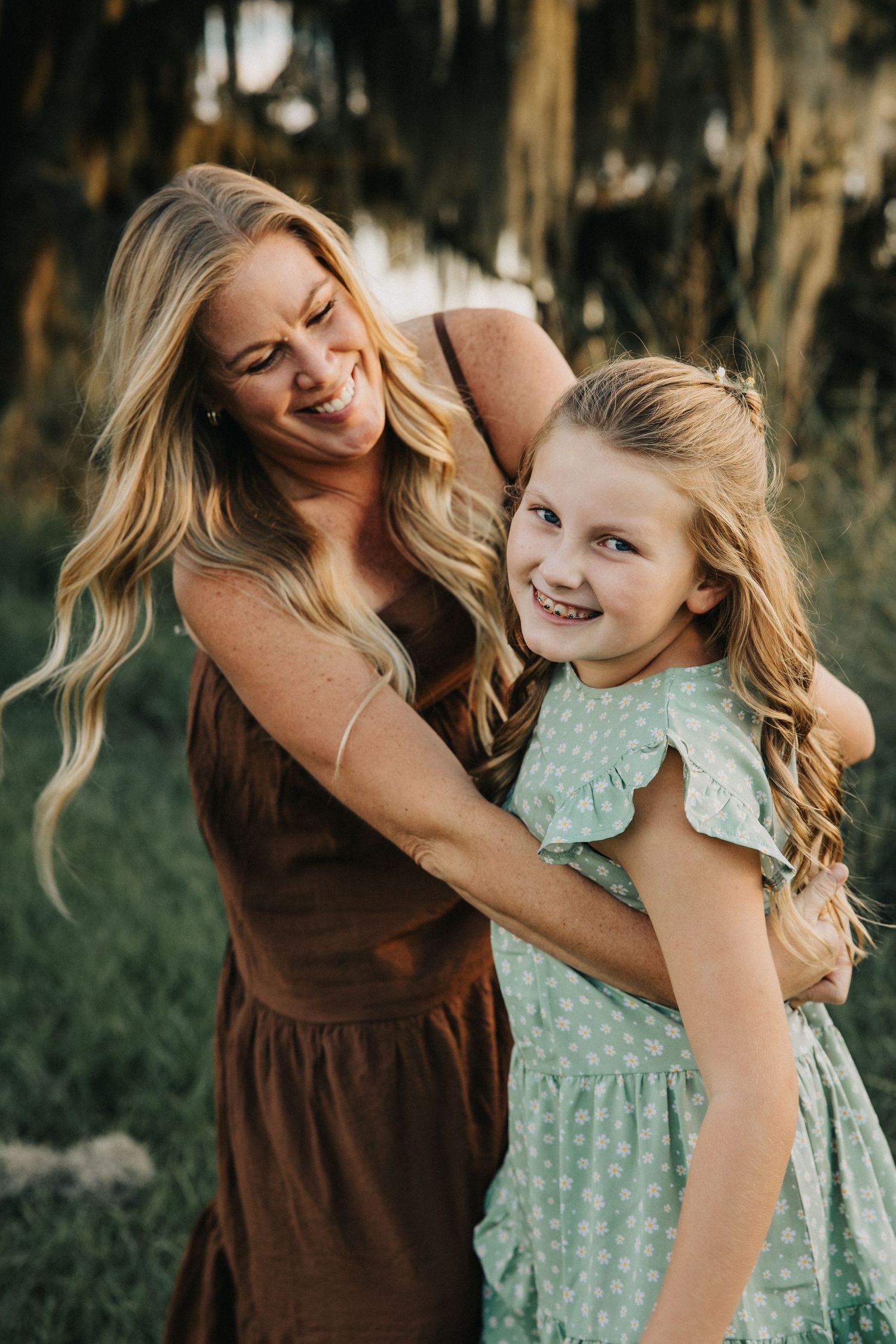 A candid laughing moment photographed in warm lighting with Spanish moss trees in the background.