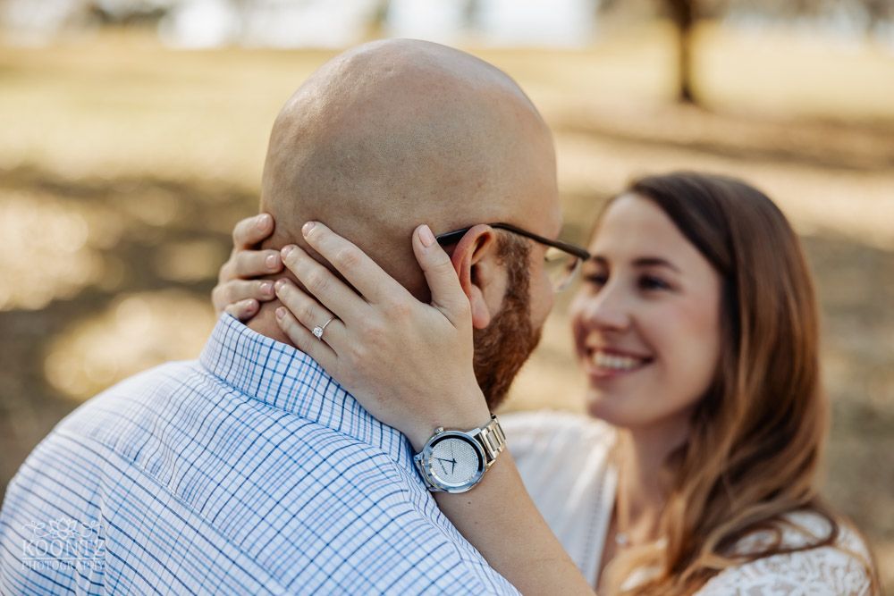 A tender romantic moment captured outdoors between a couple sharing an intimate gesture.