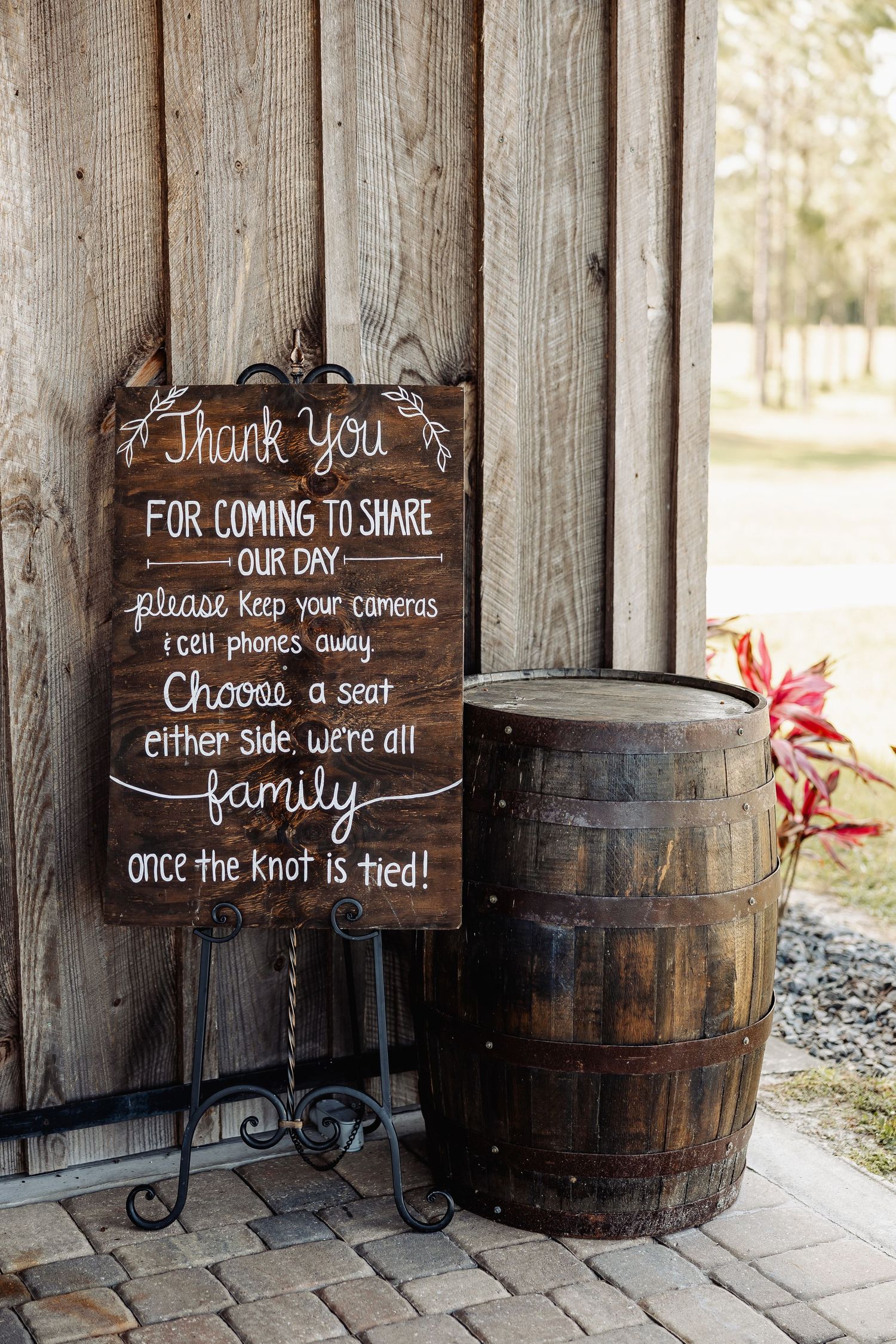 Wooden welcome sign and barrel decor at rustic wedding venue entrance.