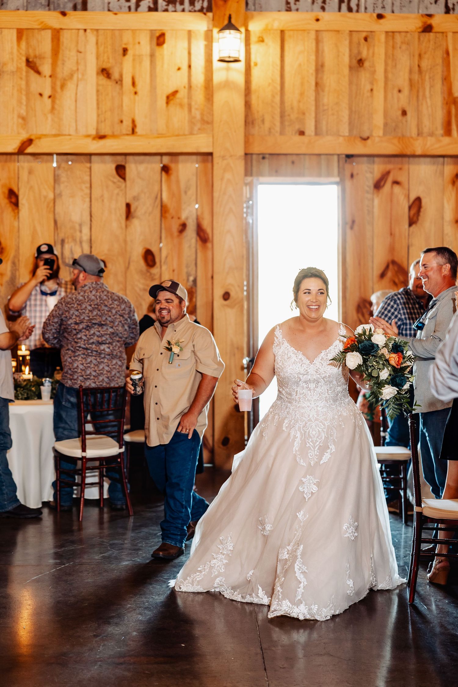 Wedding celebration in rustic barn venue with wooden walls and warm lighting.