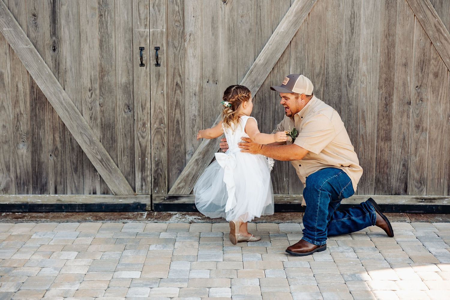 A tender moment captured between child and adult in front of a rustic barn wall.