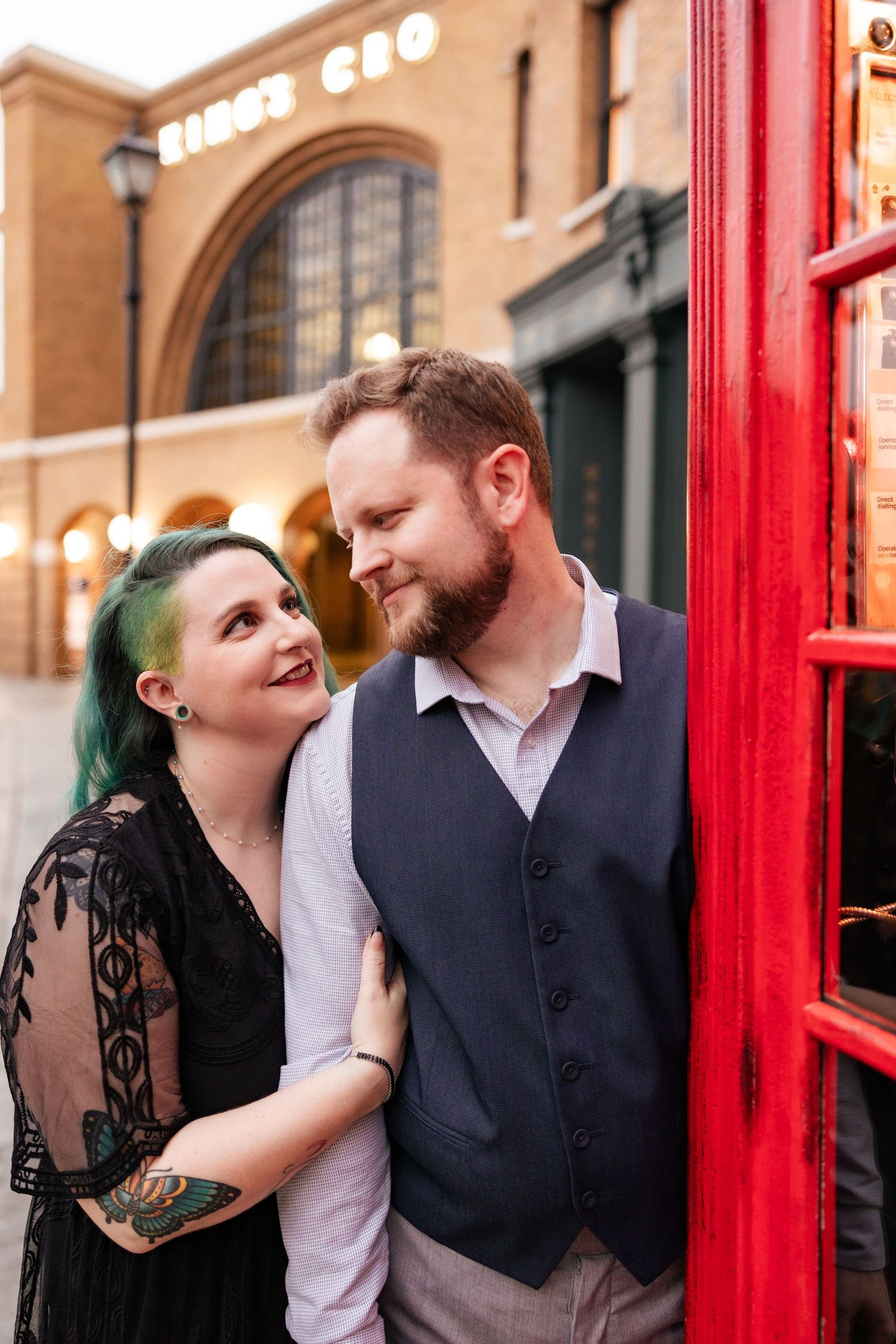 A sweet moment shared between a couple near a vintage phone booth and Kings Cross.