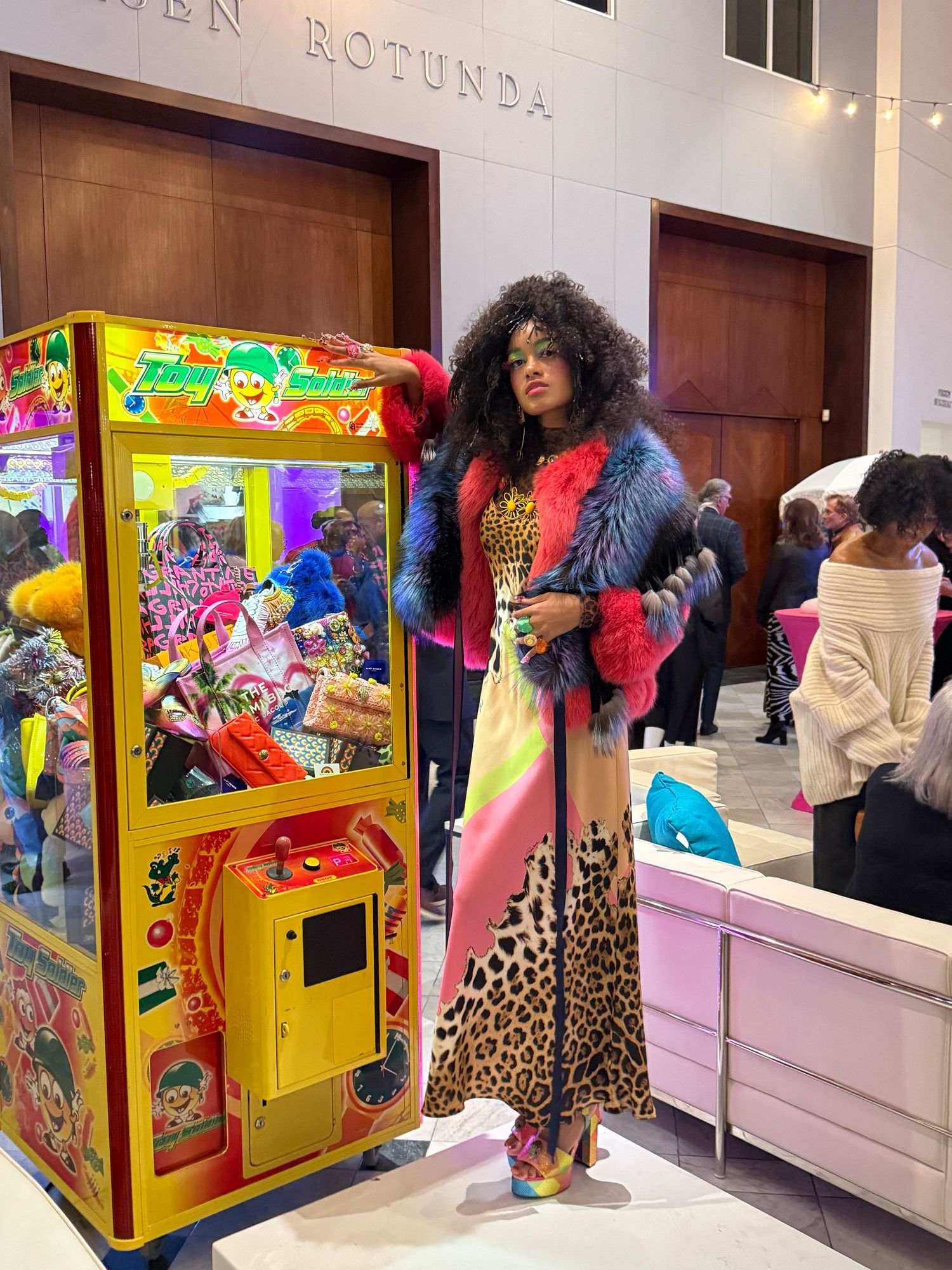 Colorful arcade claw machines and gaming cabinets line the wall of a retail space with bright neon lighting.