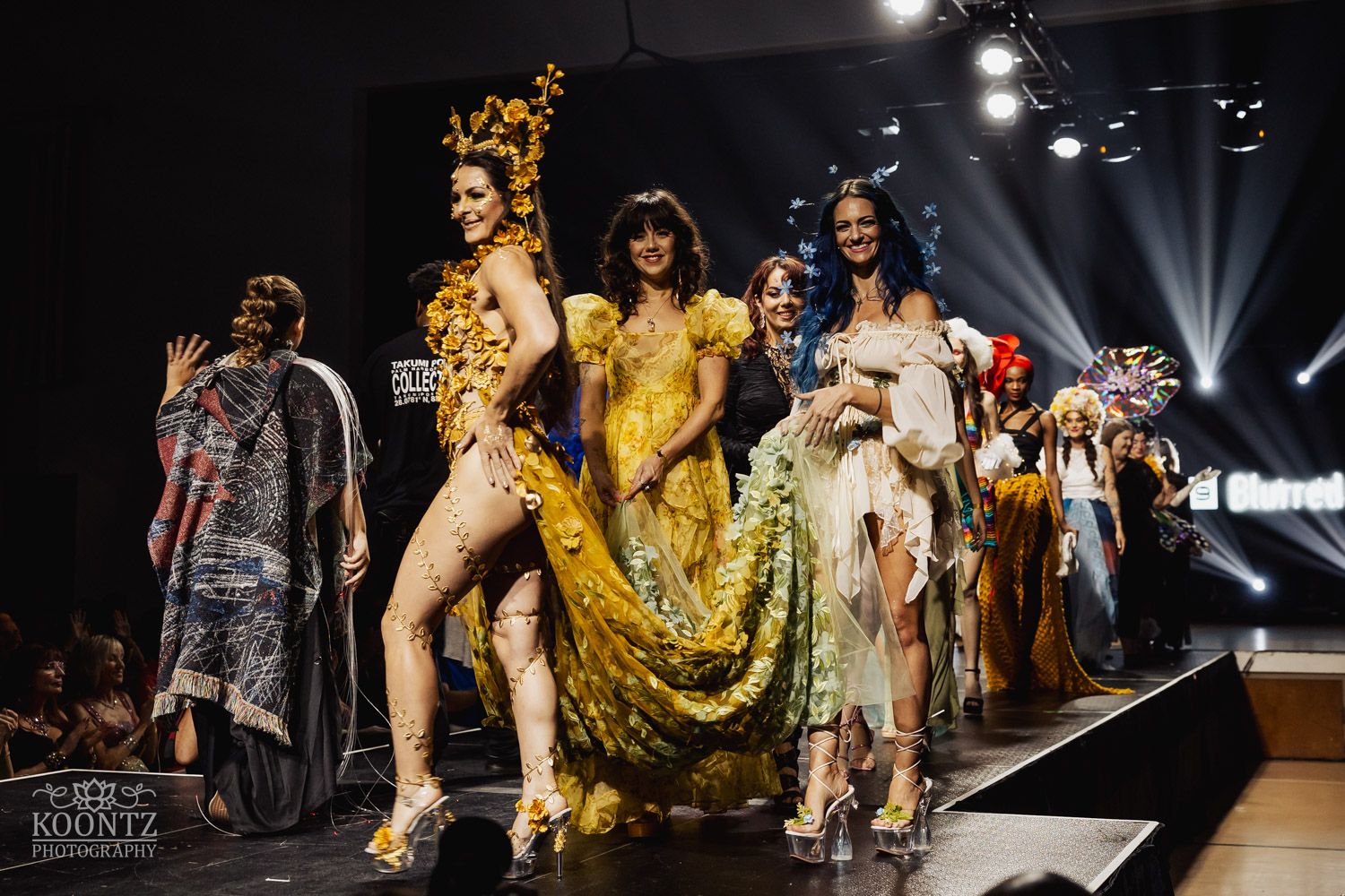Models walk runway showcasing latest fashion designs during high-end fashion show featuring bold patterns and glowing lights.
