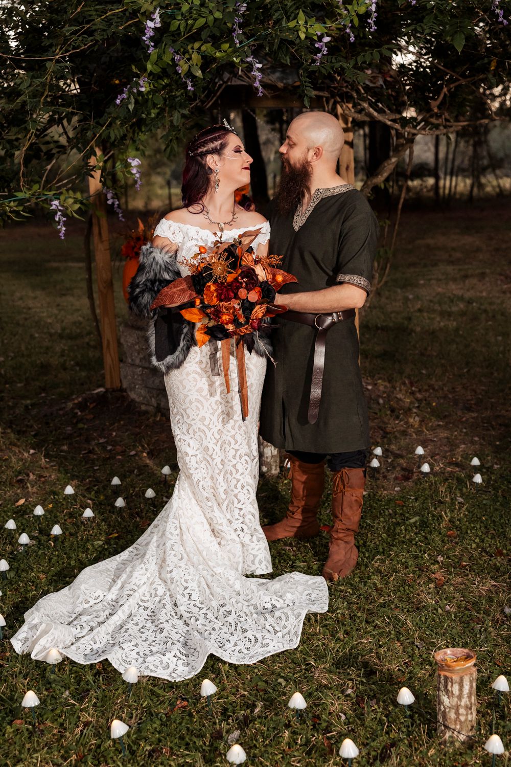 A romantic outdoor wedding scene with autumn tones, lace gown, and brown boots under a flowering tree.