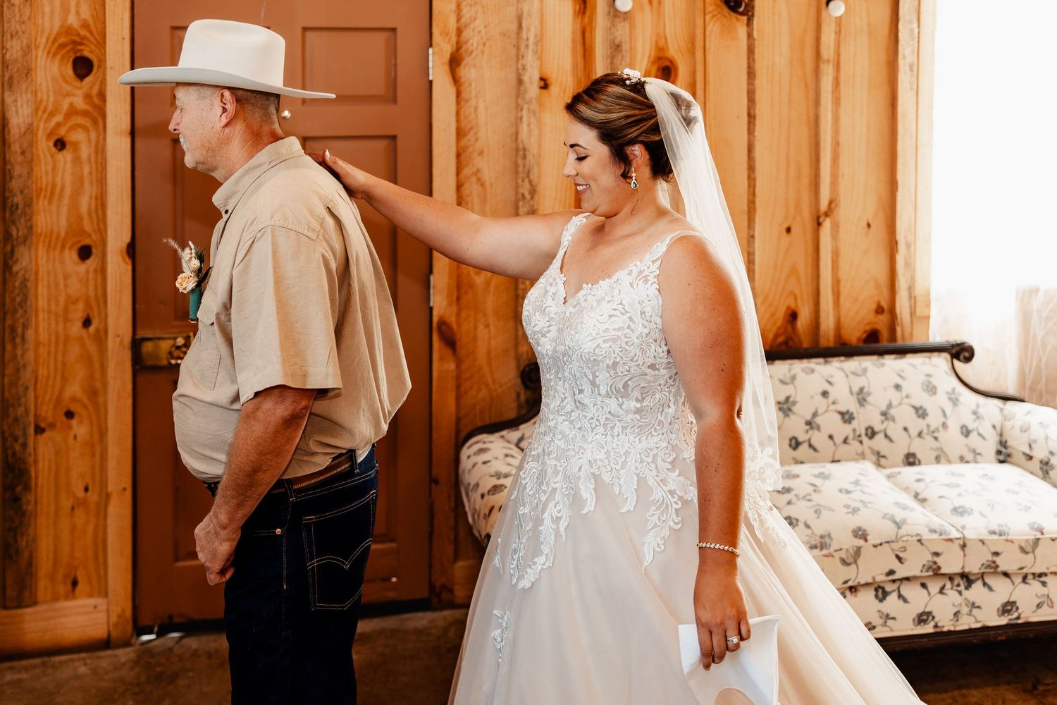 A first look wedding moment between bride and companion in a rustic wood-paneled room.