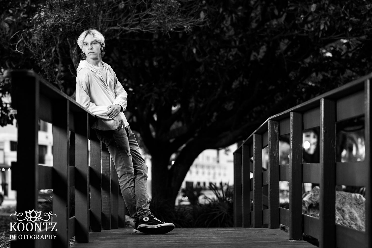 Black and white portrait on wooden bridge showing dramatic lighting and composition.