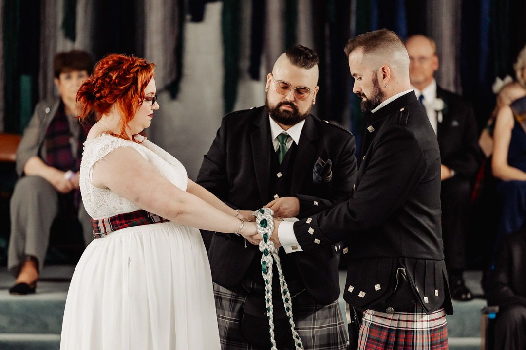 A wedding ceremony featuring traditional Celtic elements with participants in formal Scottish attire.