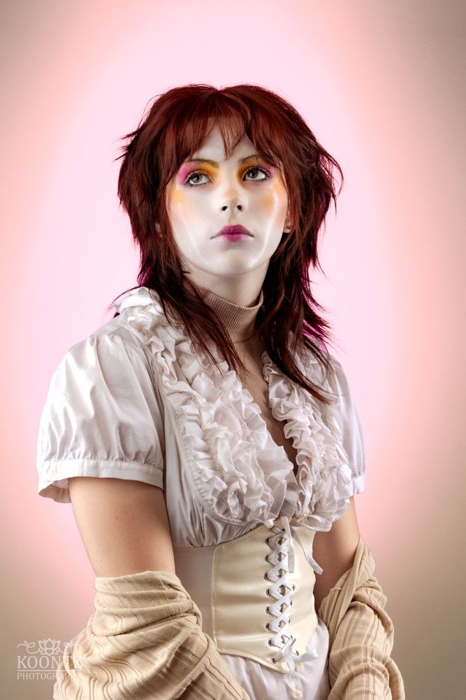 A dramatic portrait in vintage-style clothing against a pink backdrop.
