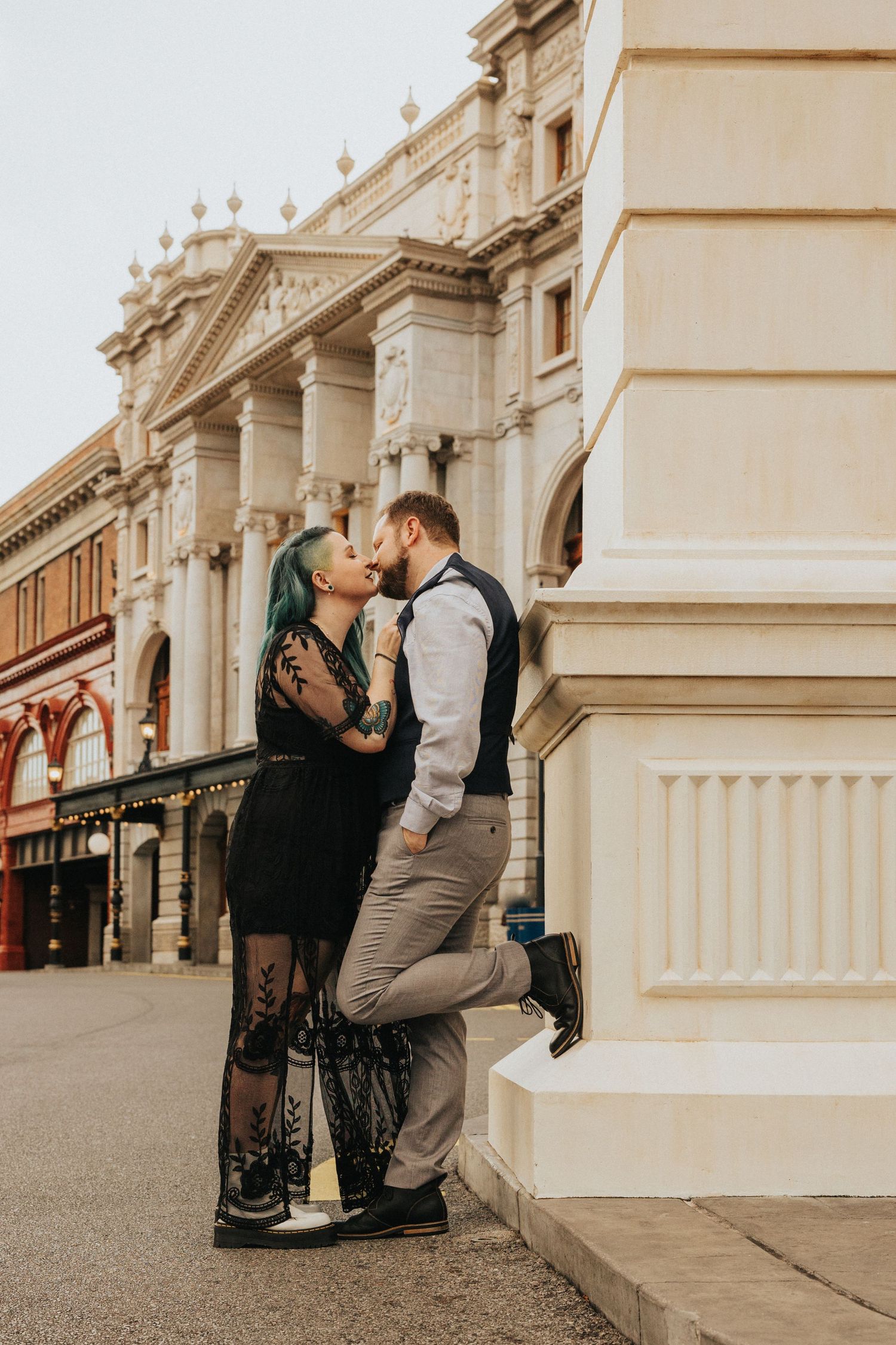Couple in formal wear posing romantically against ornate classical architecture.