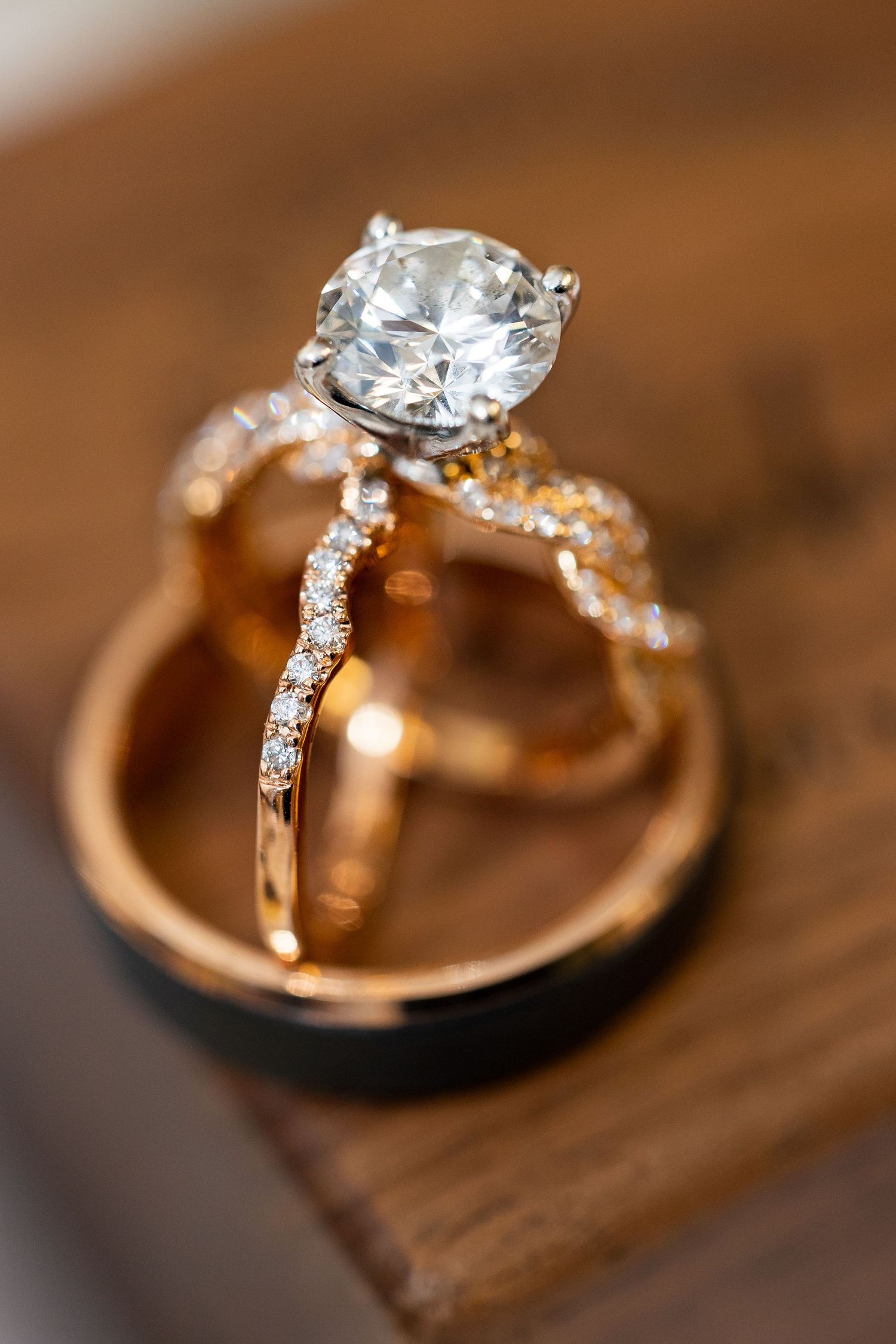 Close-up of a stunning round diamond engagement ring with rose gold band and diamond wedding rings.