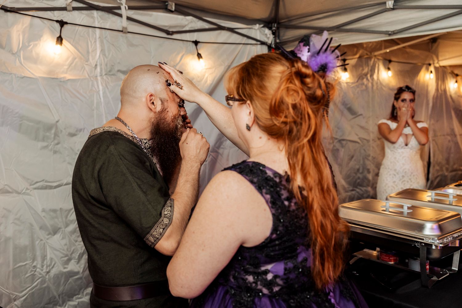 Reception guests enjoying treats and conversation under string lights at wedding celebration.