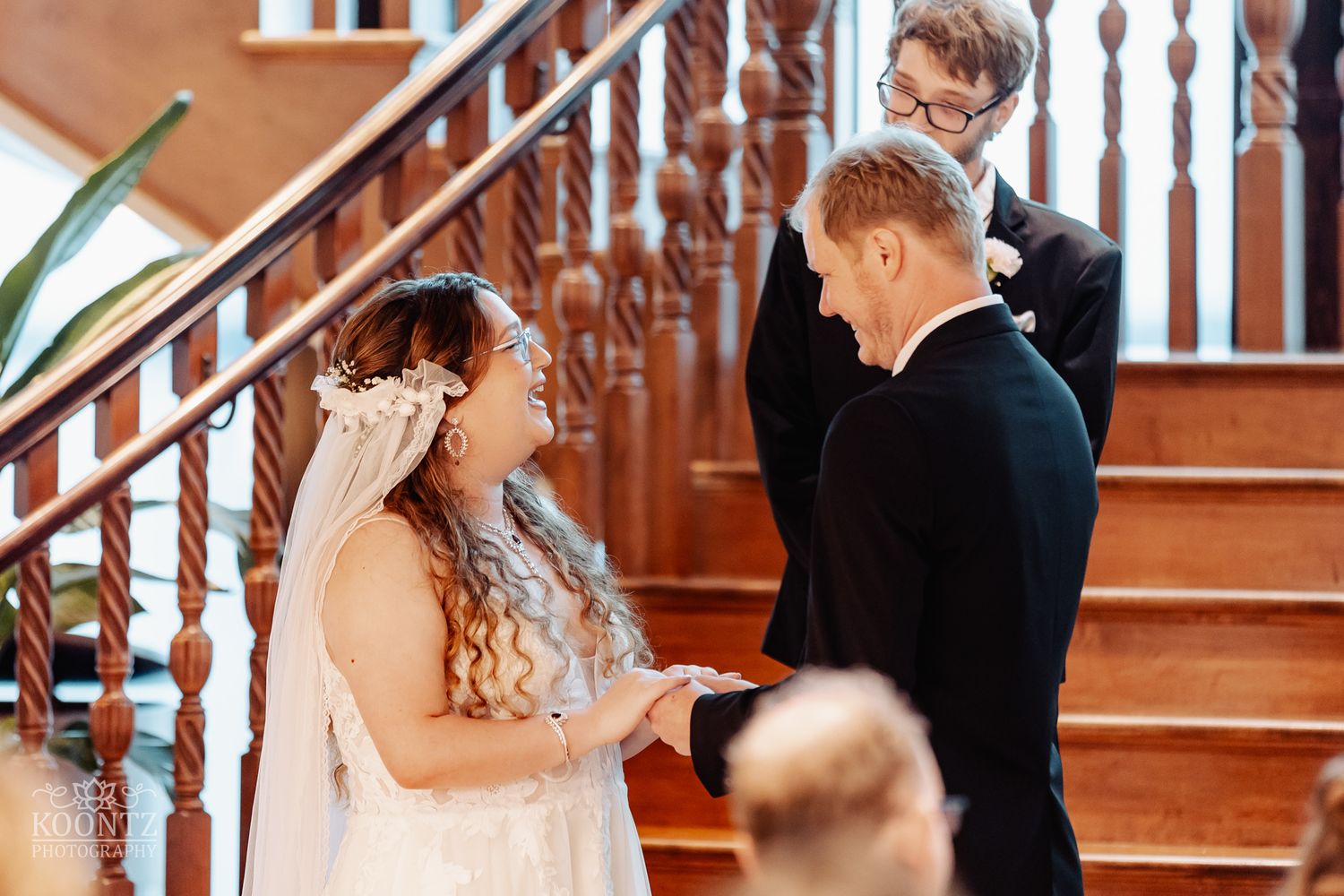 Intimate wedding ceremony moment on wooden staircase with warm lighting.
