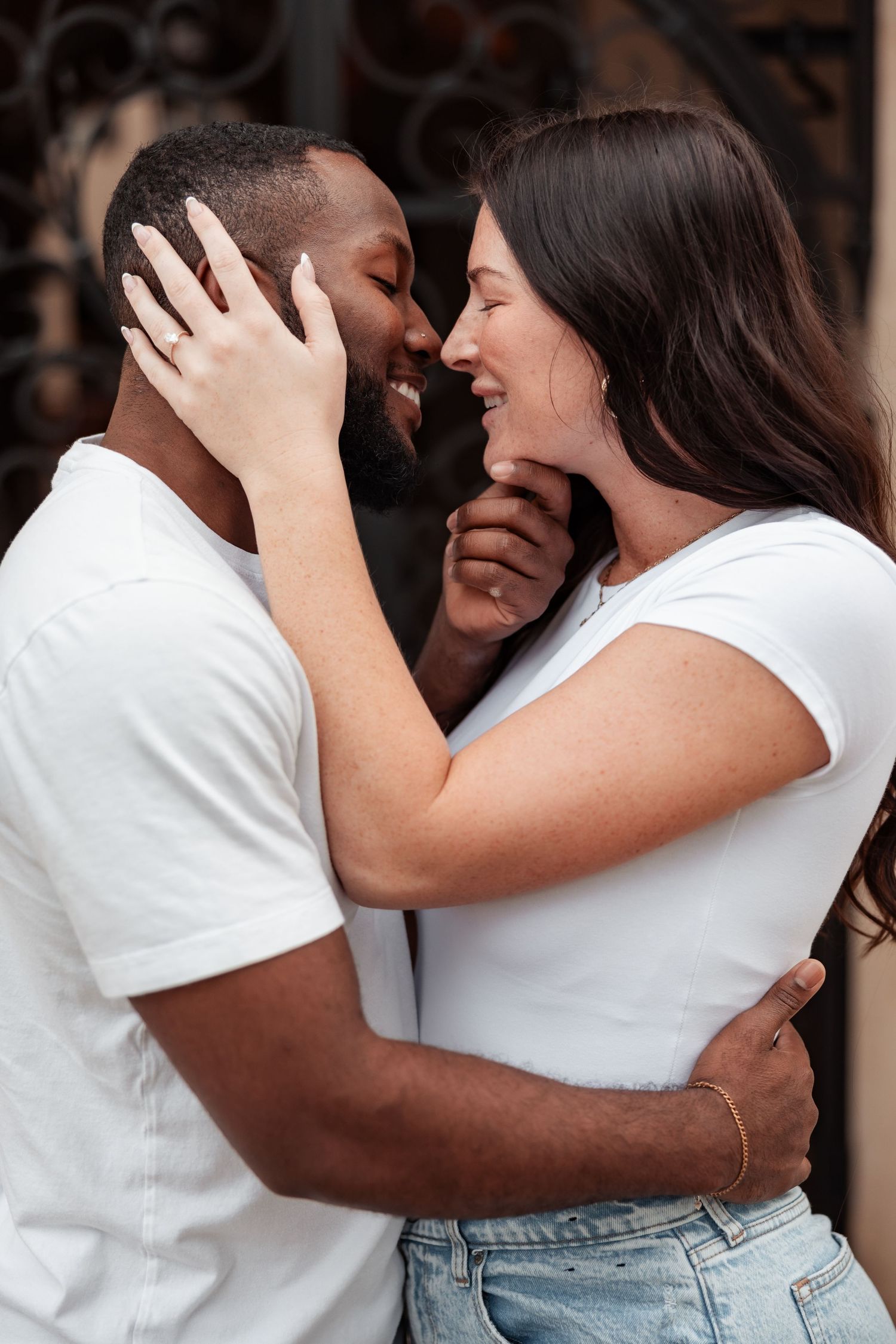 Intimate romantic moment between couple wearing white shirts against dark background.