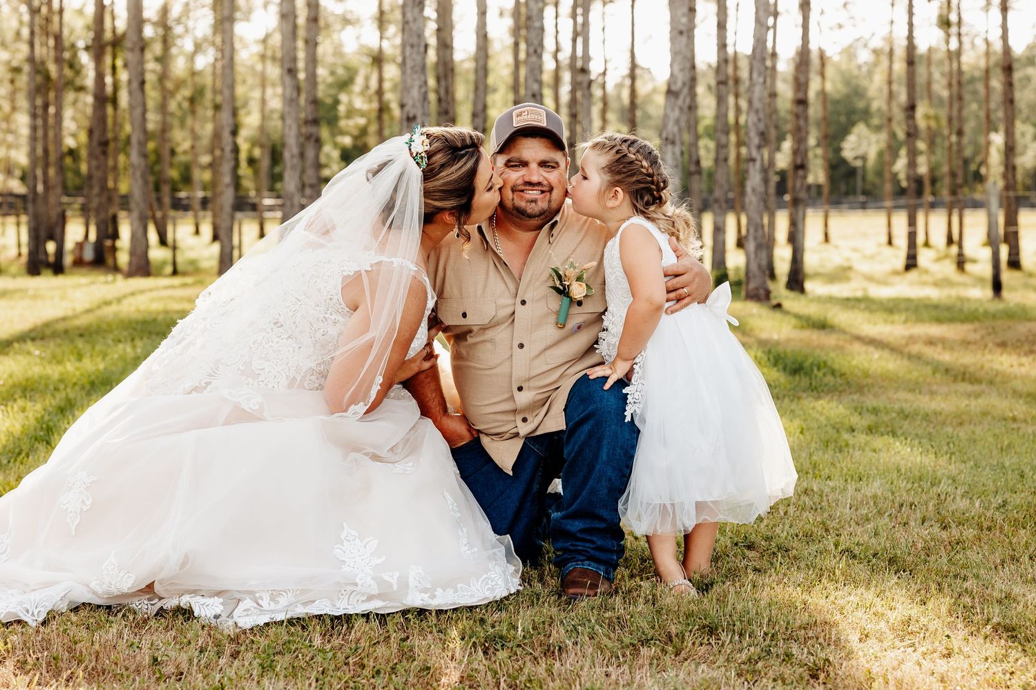 A joyful wedding moment captured outdoors in a sunlit forest setting with white wedding attire.